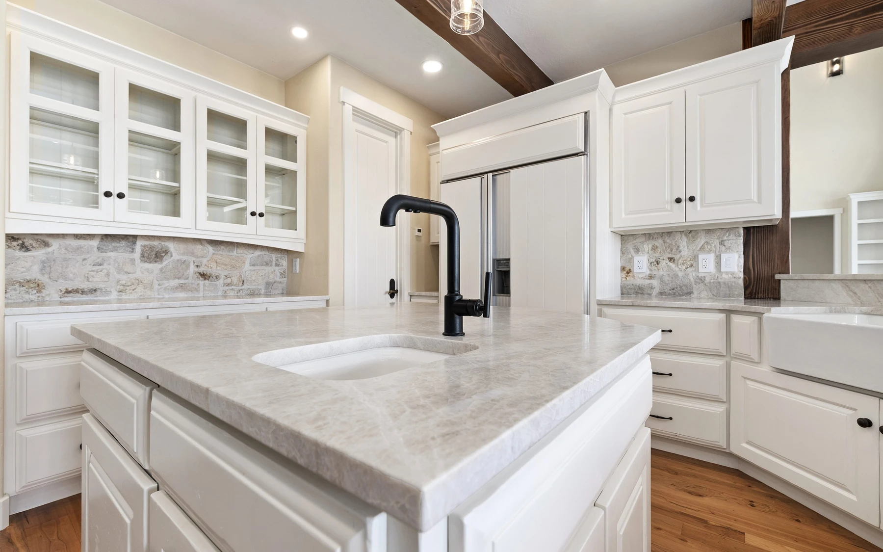 Kitchen in the Club Hill Refresh remodel at Whitetail Club, with wood cabinetry, a broad countertop, and integrated appliances.