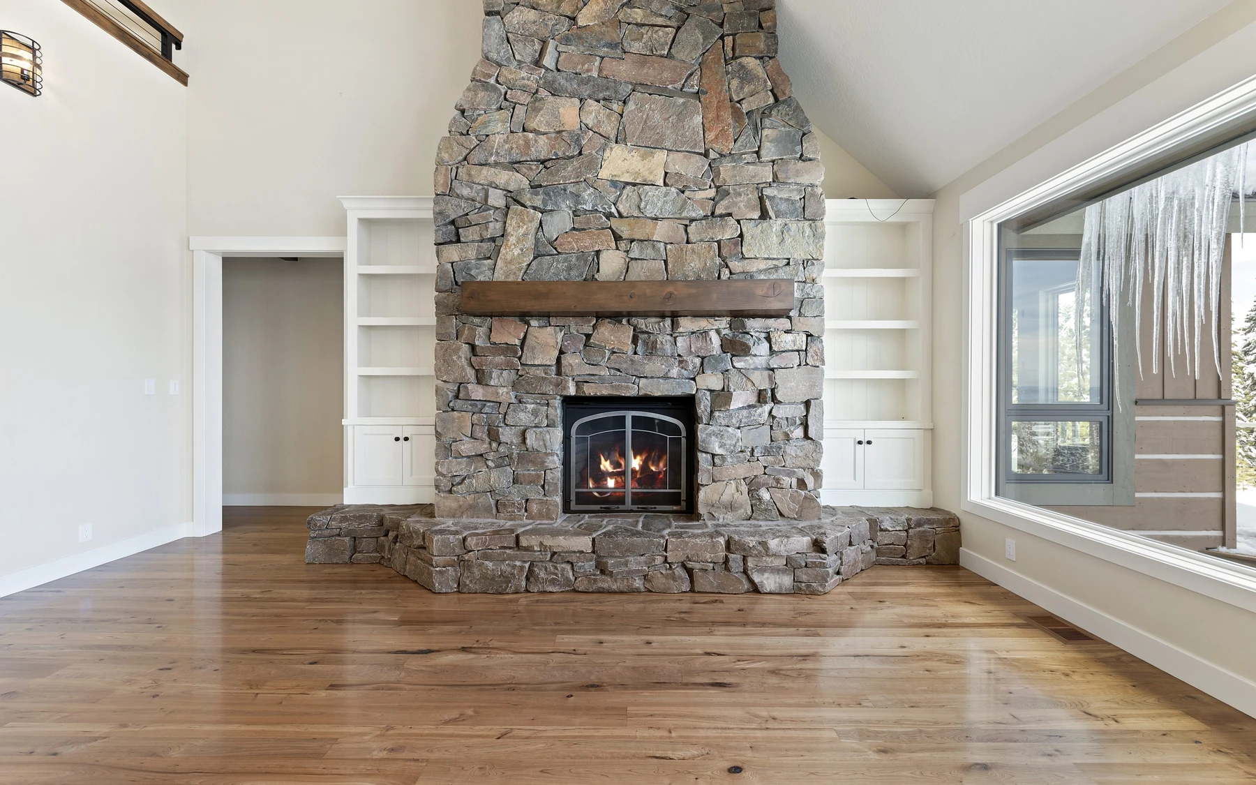 Living room in the Club Hill Refresh remodel at Whitetail Club, with a fireplace, large windows, and warm wood finishes.
