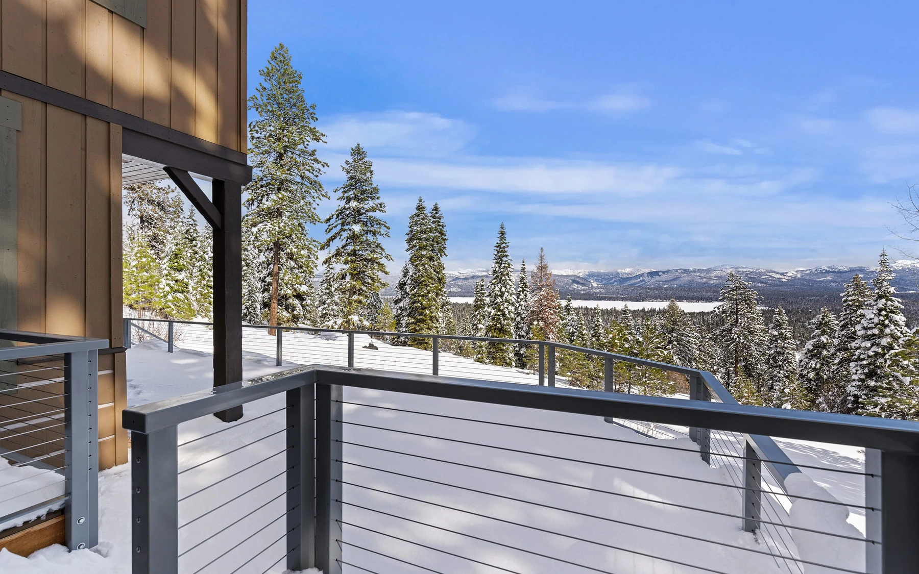 Exterior of the Club Hill Refresh remodel at Whitetail Club, showing wood siding and timber details, the surrounding forest, and snow-covered grounds.
