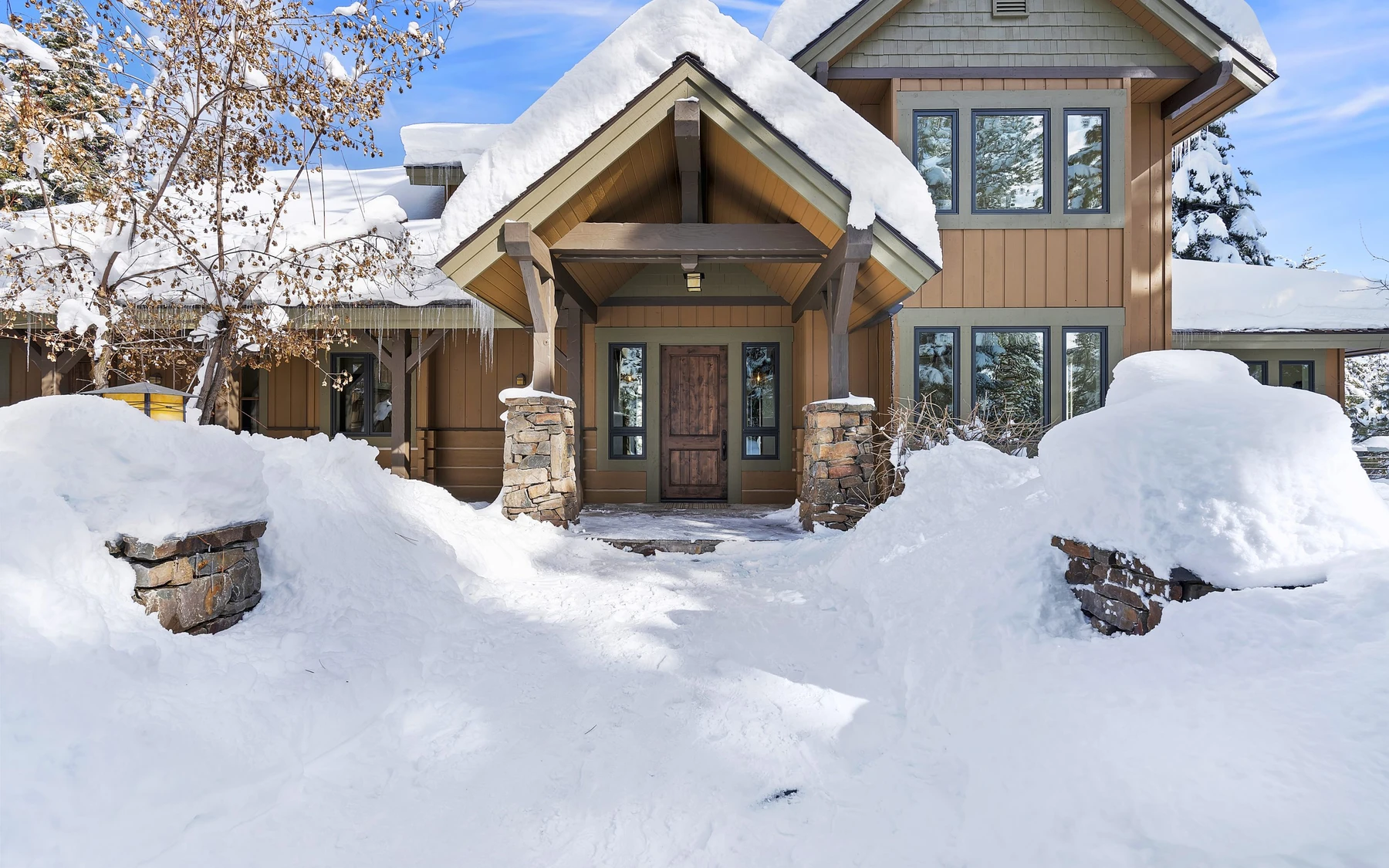 Exterior of the Club Hill Refresh remodel at Whitetail Club, showing wood siding and timber details, large windows, and snow-covered grounds.