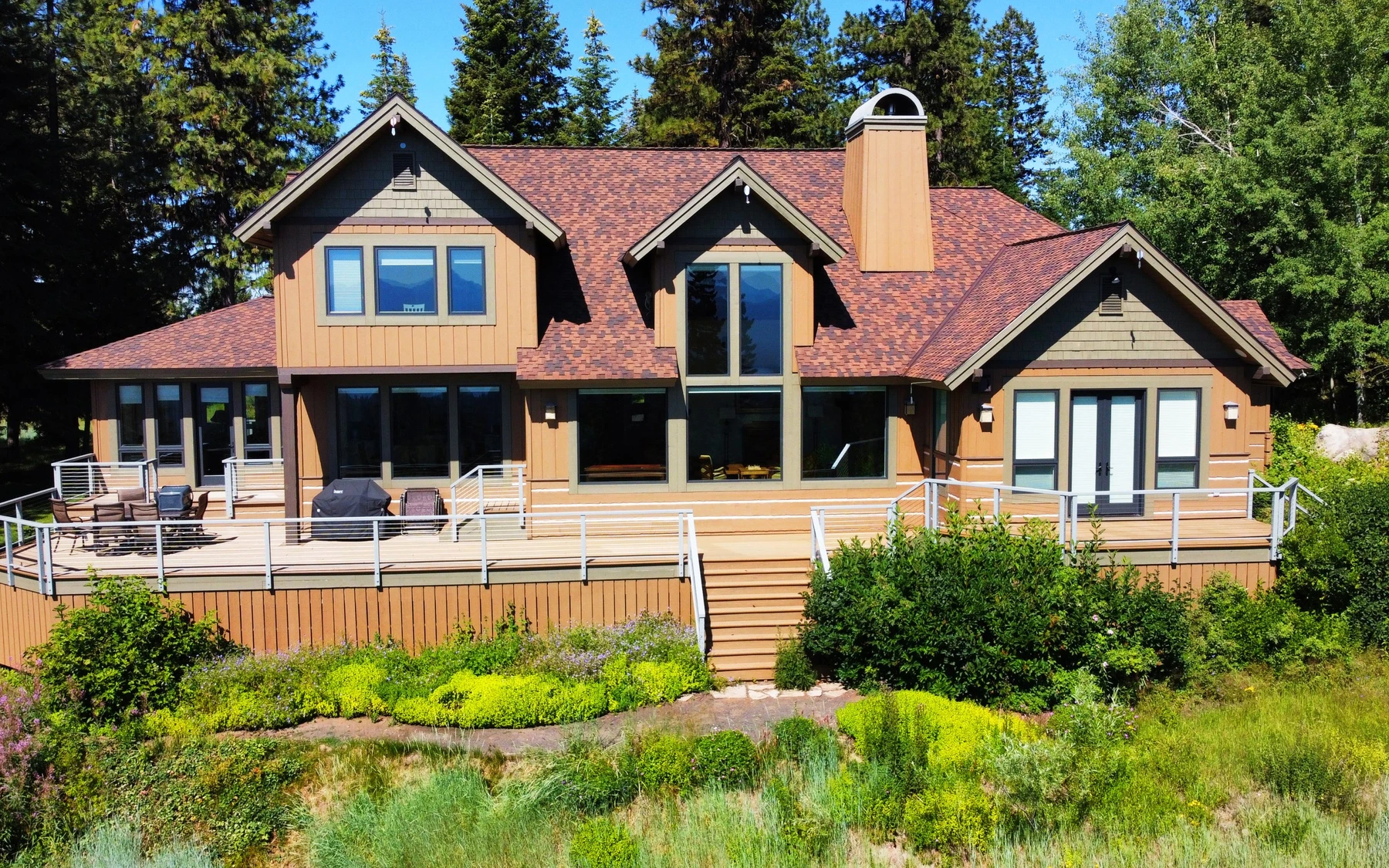 Exterior of the Club Hill Refresh remodel at Whitetail Club, showing large windows and the surrounding forest.