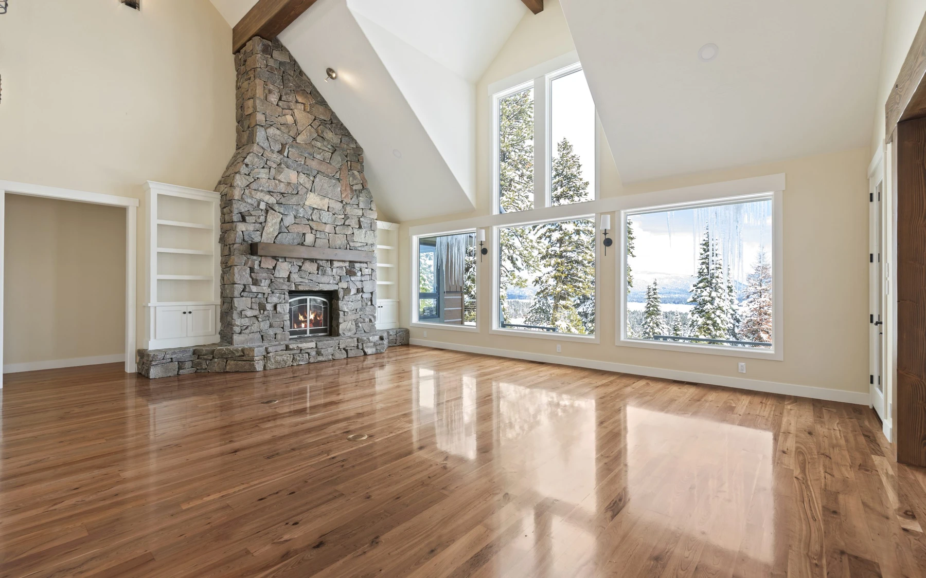 Living room in the Club Hill Refresh remodel at Whitetail Club, with a fireplace, large windows, and warm wood finishes.