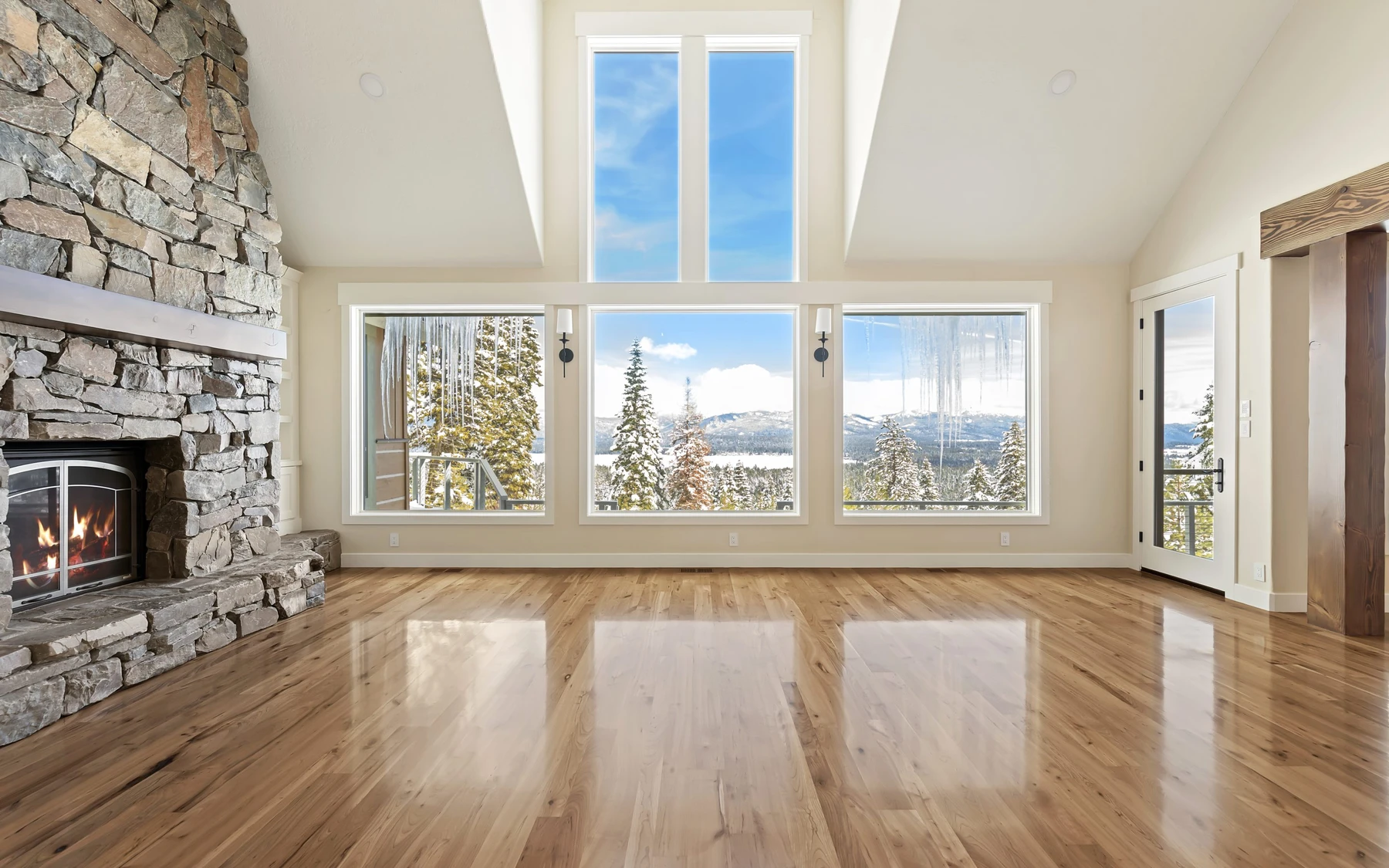 Living room in the Club Hill Refresh remodel at Whitetail Club, with a fireplace, large windows, and warm wood finishes.