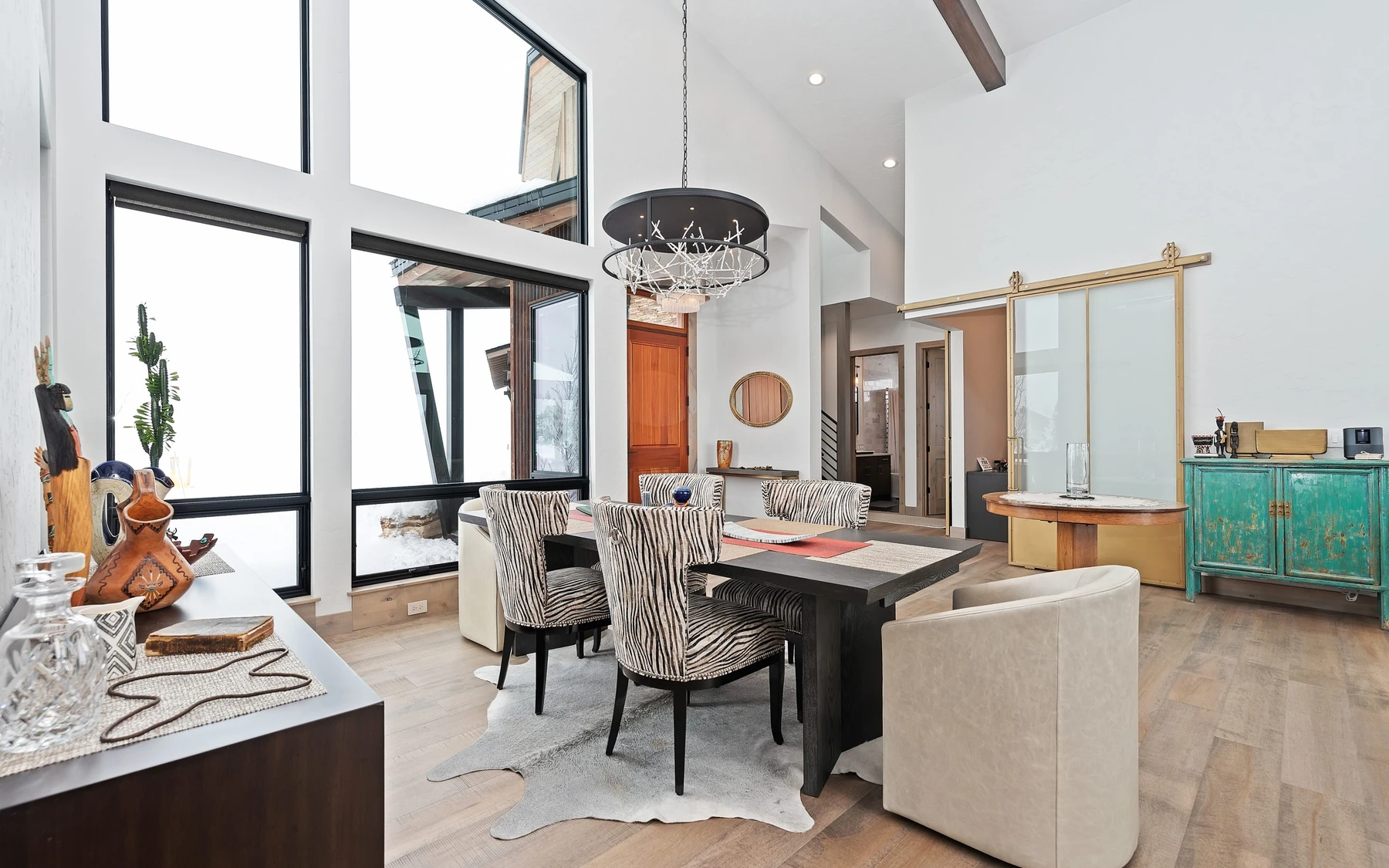 Dining room in the Contemporary Hideaway custom home near McCall, with a dining table, statement lighting, and large windows.
