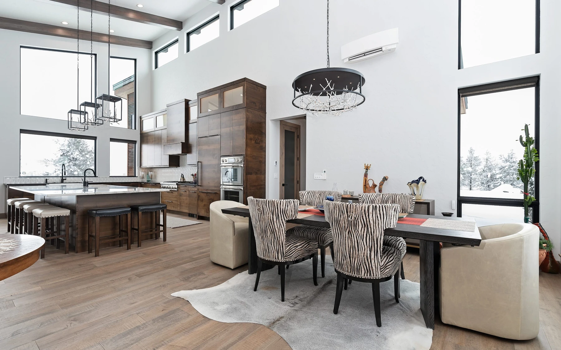 Dining room in the Contemporary Hideaway custom home near McCall, with a dining table, statement lighting, and large windows.