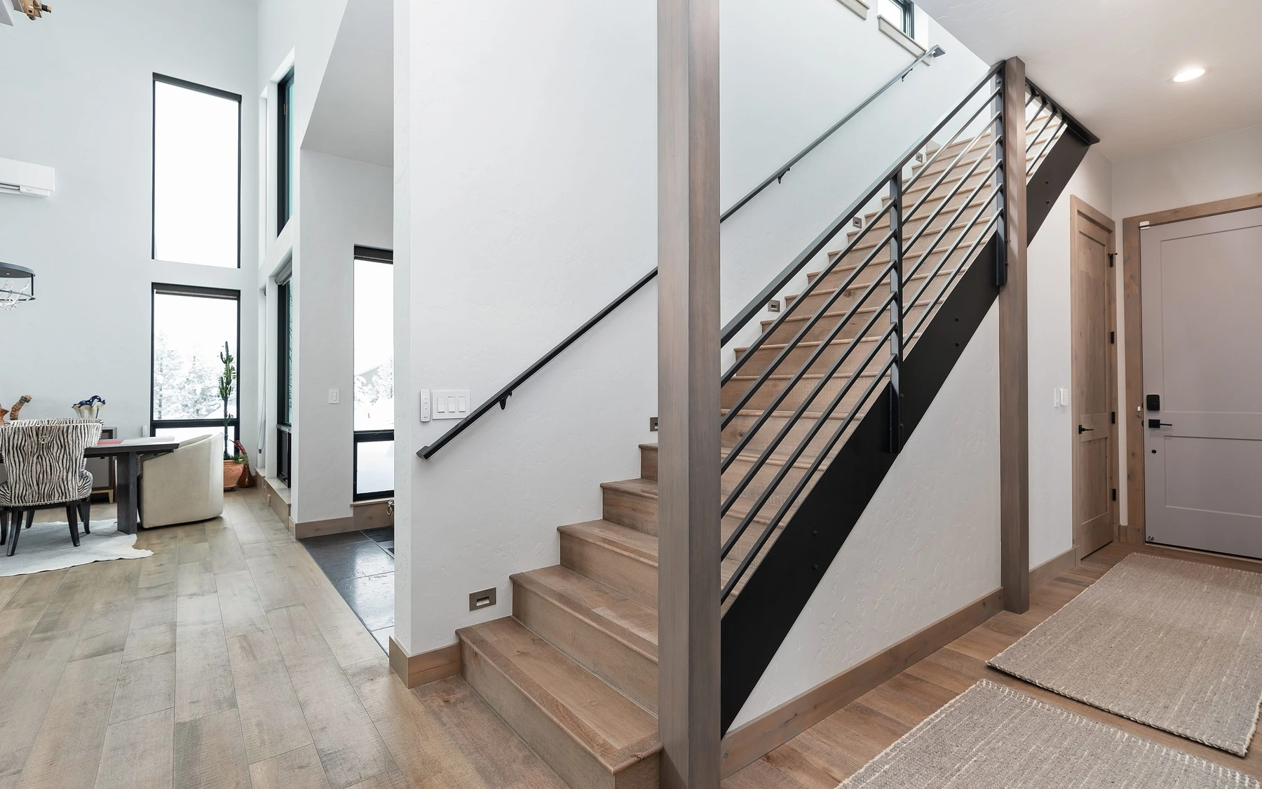 Stair hall in the Contemporary Hideaway custom home near McCall, with a custom staircase, wood railings, and natural light.