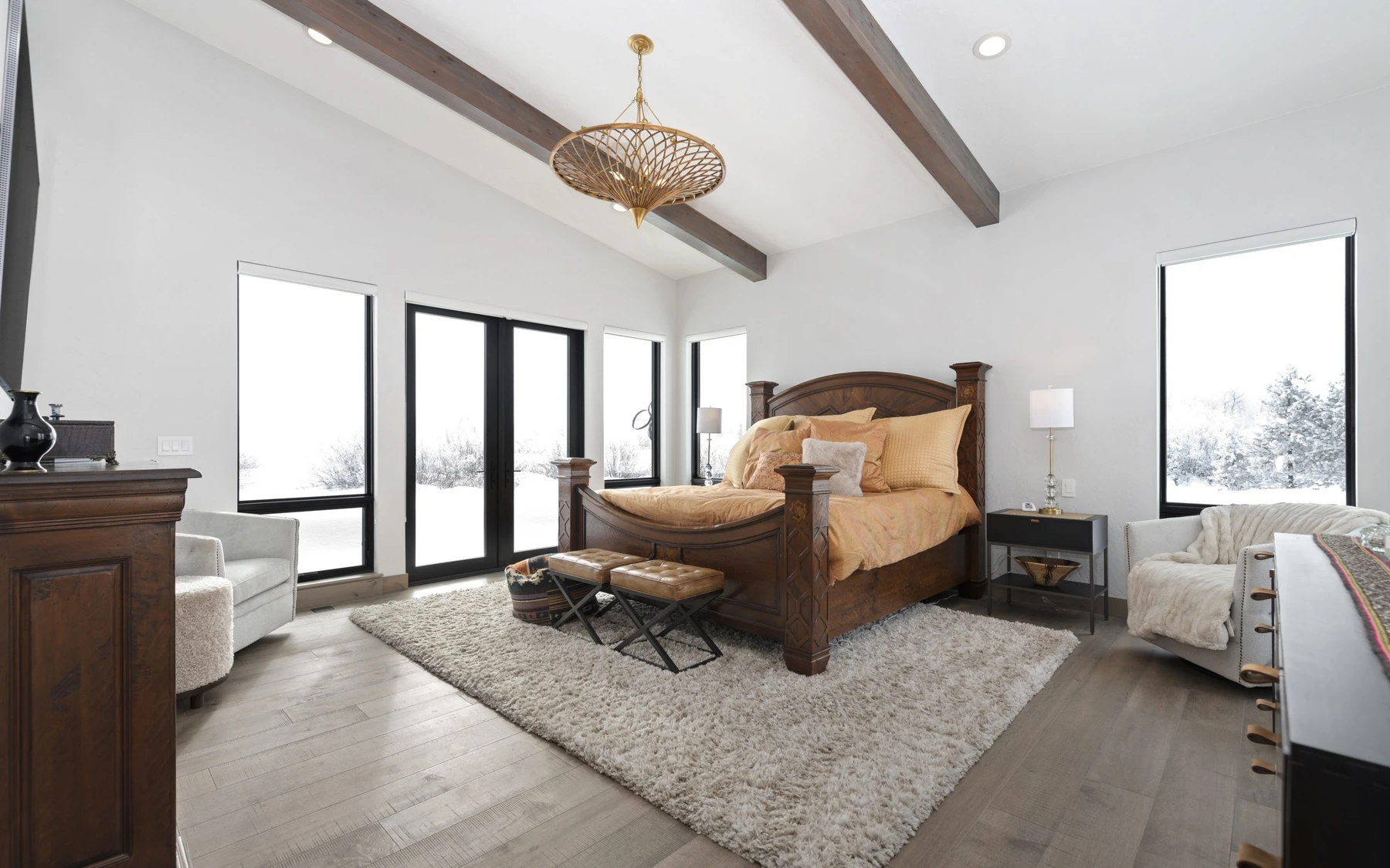 Bedroom in the Contemporary Hideaway custom home near McCall, with a layered bed, large windows, and wood details.