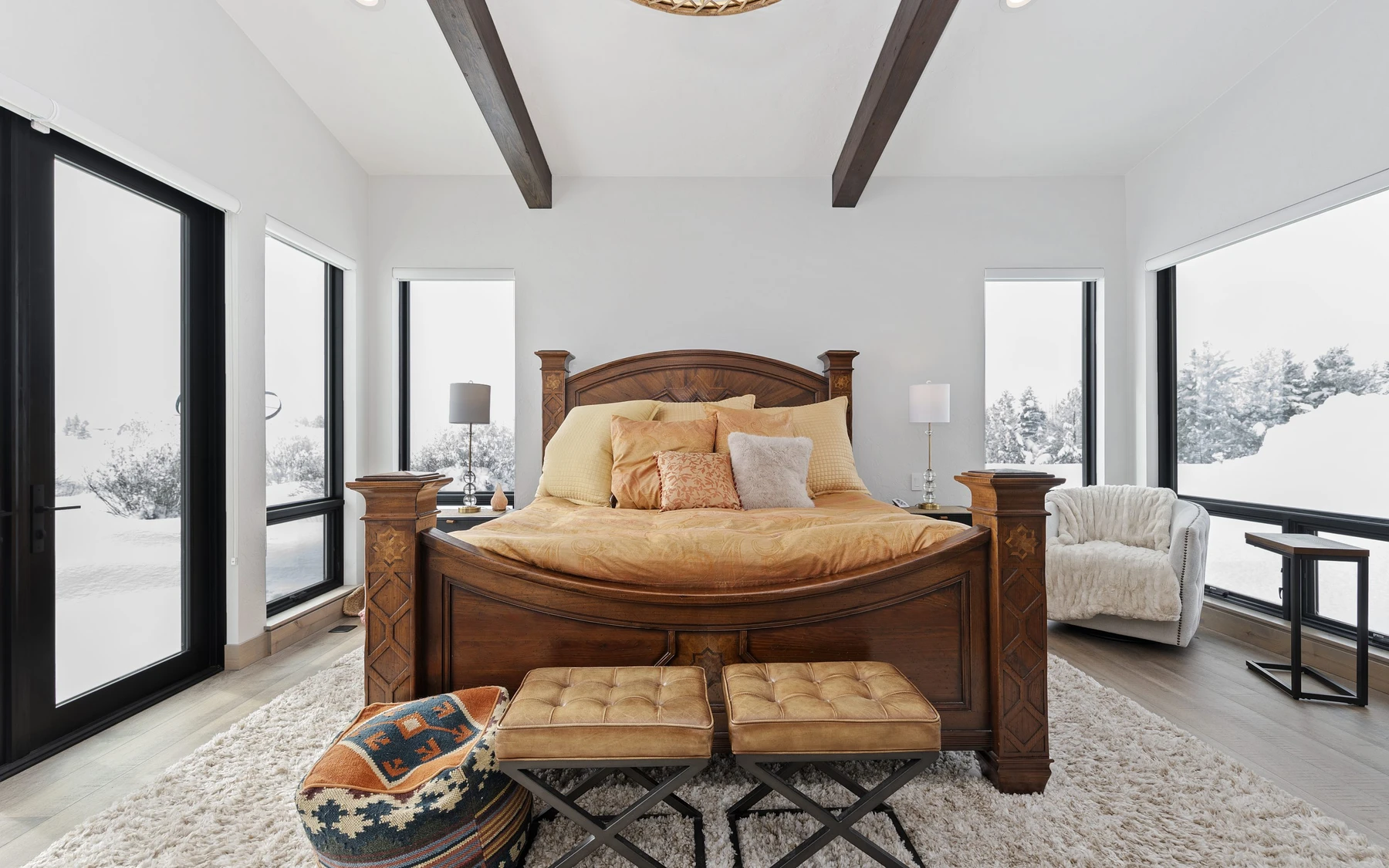 Bedroom in the Contemporary Hideaway custom home near McCall, with a layered bed, large windows, and wood details.