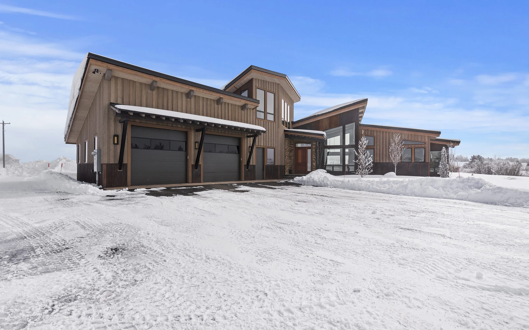 Exterior of the Contemporary Hideaway custom home near McCall, showing large windows and snow-covered grounds.