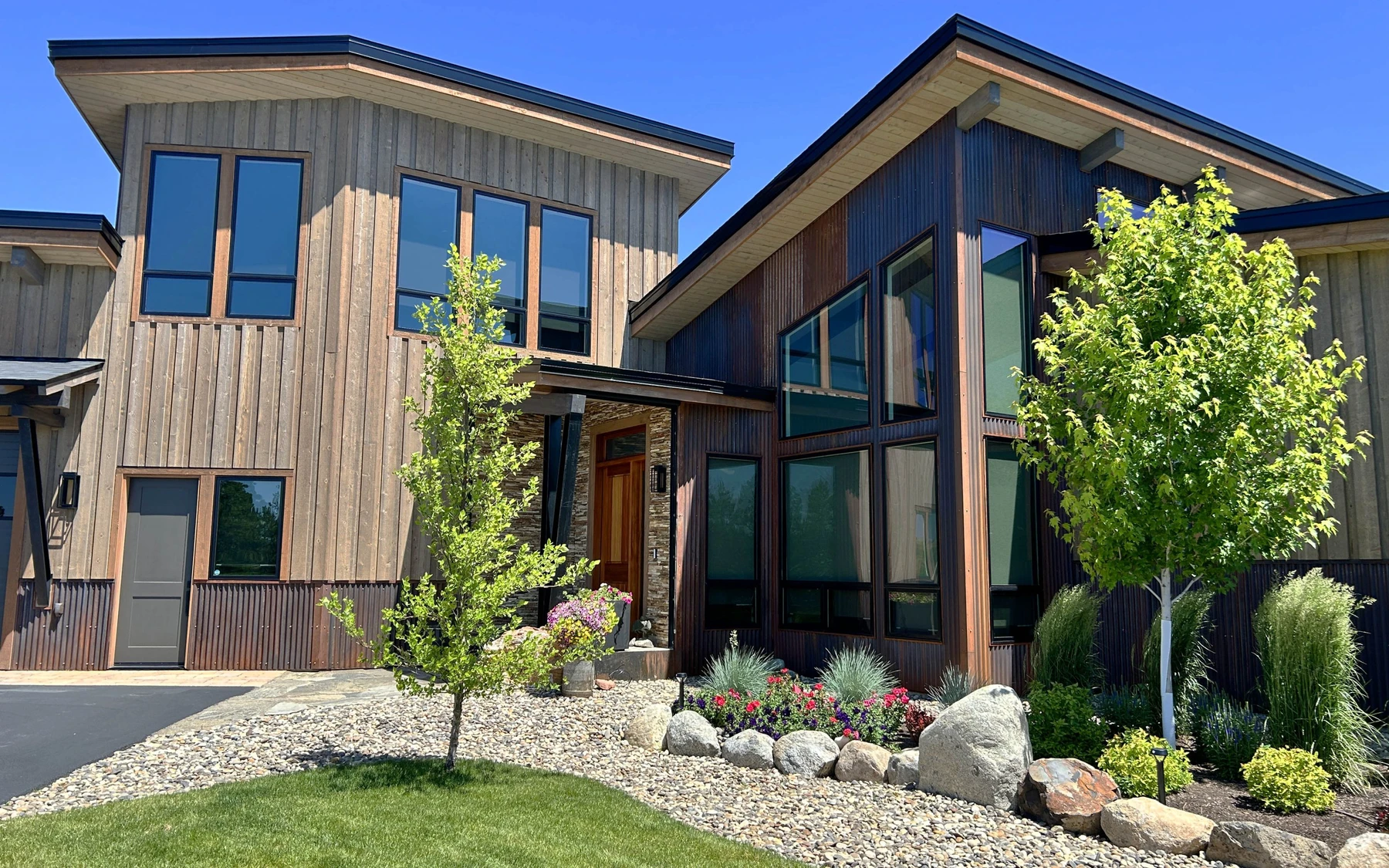 Exterior of the Contemporary Hideaway custom home near McCall, showing wood siding and timber details, stonework, and large windows.