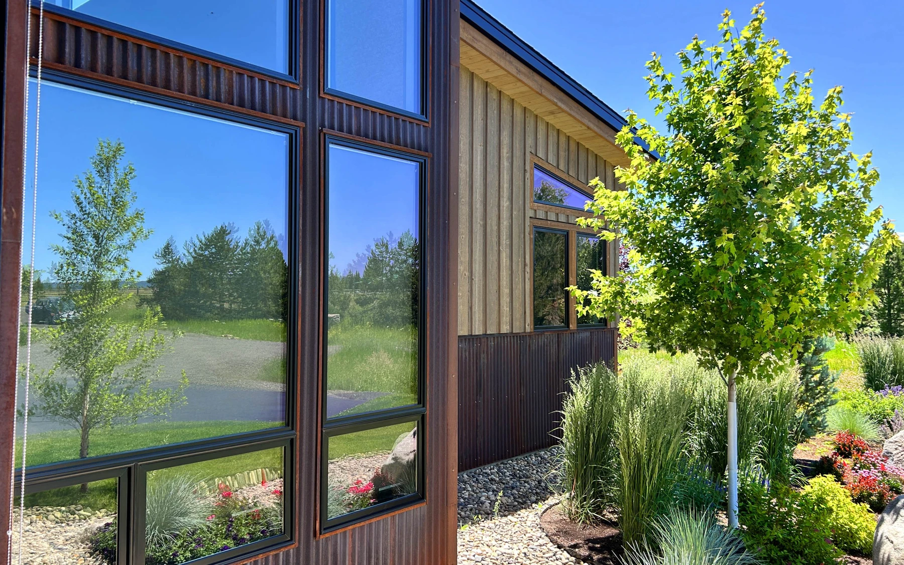 Exterior of the Contemporary Hideaway custom home near McCall, showing wood siding and timber details, stonework, and large windows.