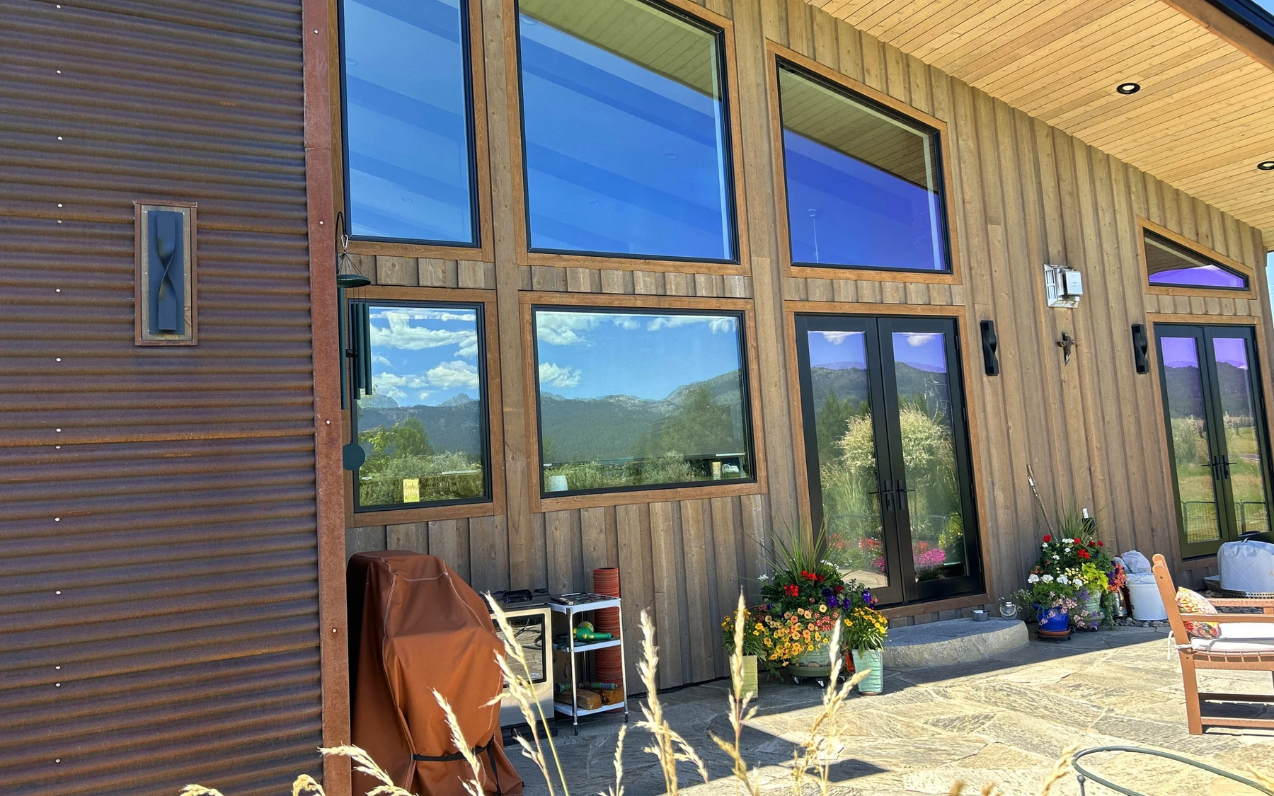 Exterior of the Contemporary Hideaway custom home near McCall, showing wood siding and timber details and large windows.