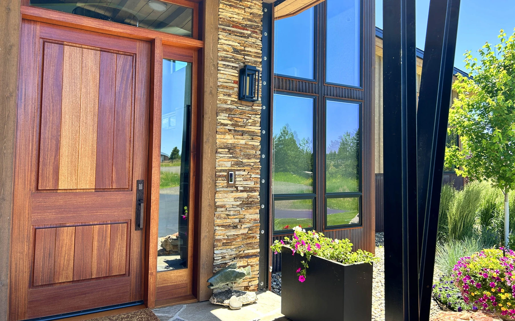 Exterior of the Contemporary Hideaway custom home near McCall, showing wood siding and timber details, stonework, and large windows.
