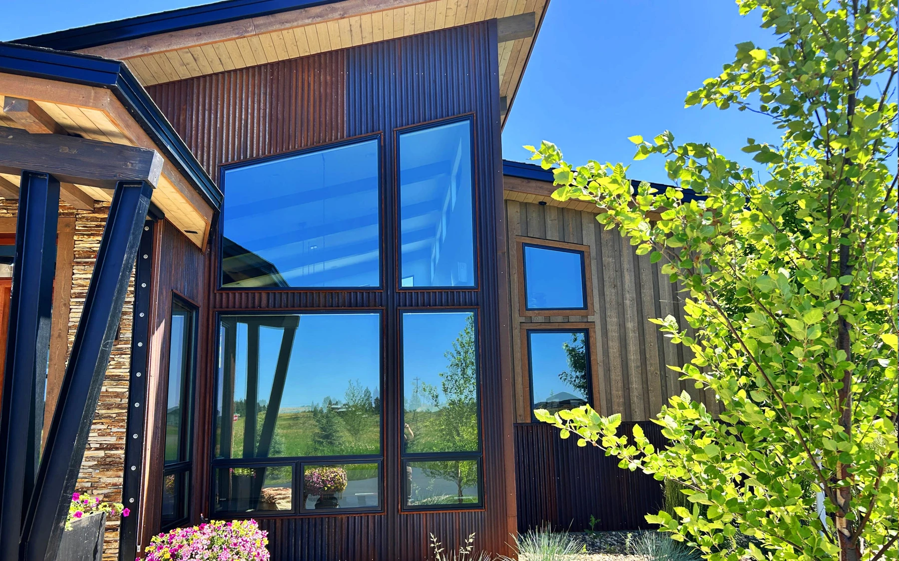 Exterior of the Contemporary Hideaway custom home near McCall, showing wood siding and timber details, stonework, and large windows.