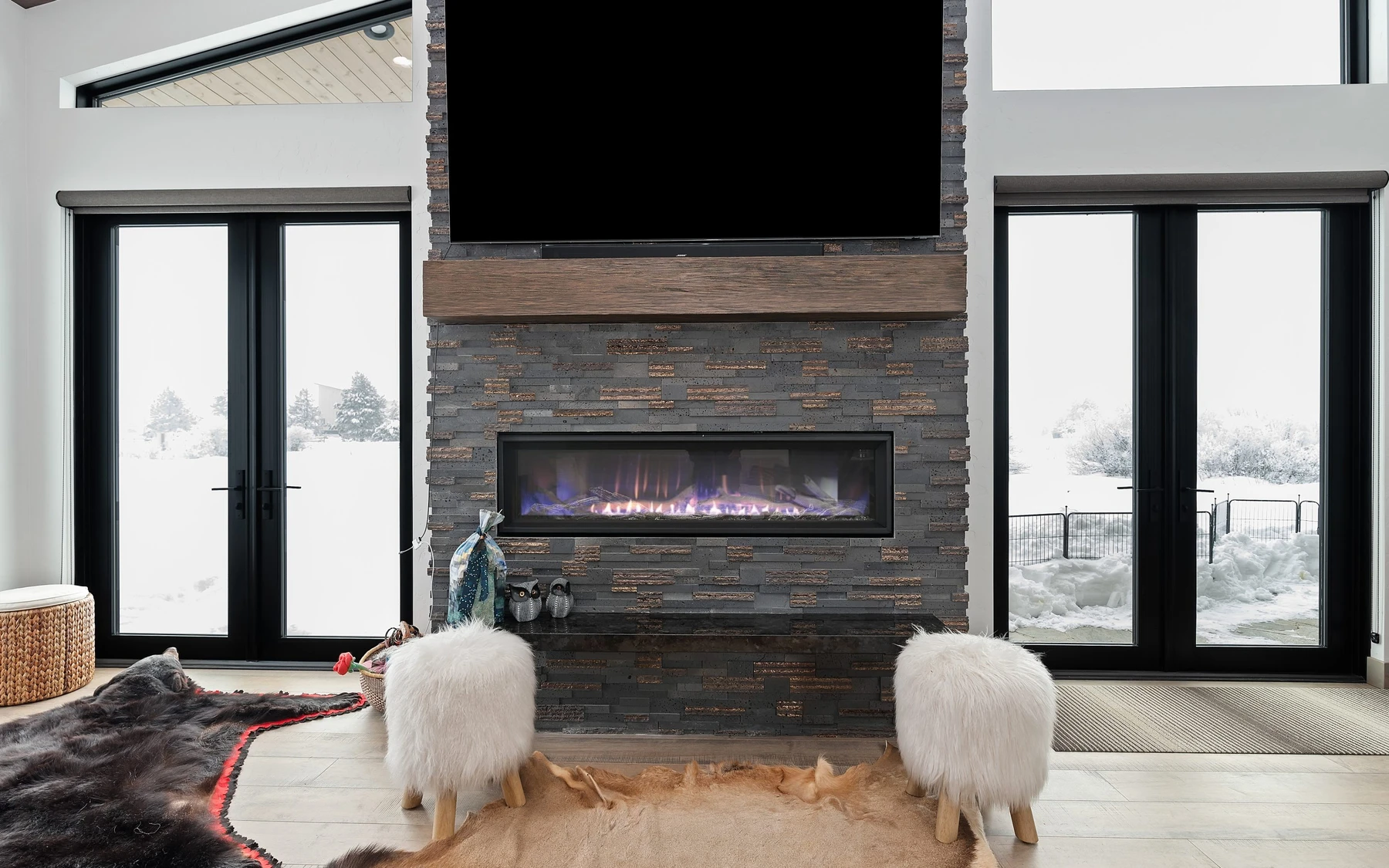 Living room in the Contemporary Hideaway custom home near McCall, with a fireplace, large windows, and warm wood finishes.