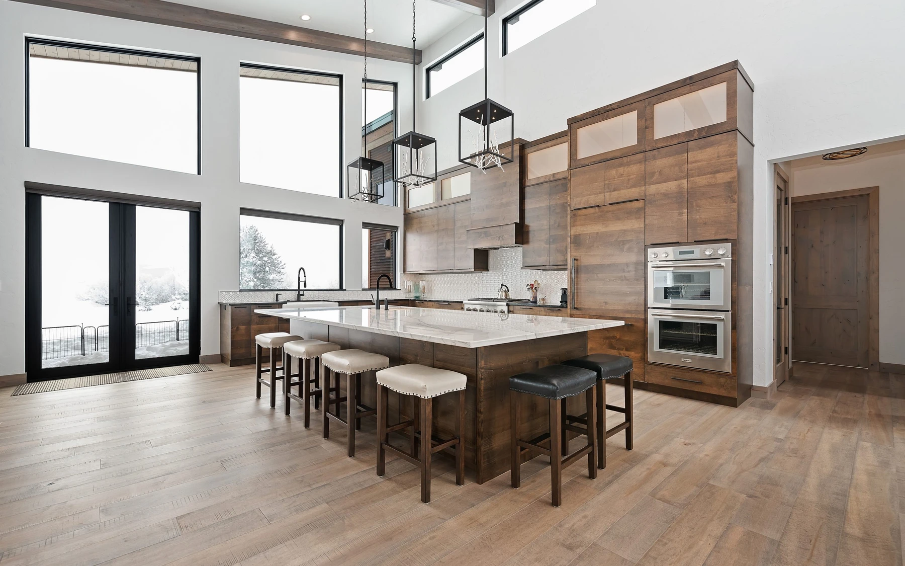 Kitchen in the Contemporary Hideaway custom home near McCall, with wood cabinetry, integrated appliances, and large windows.