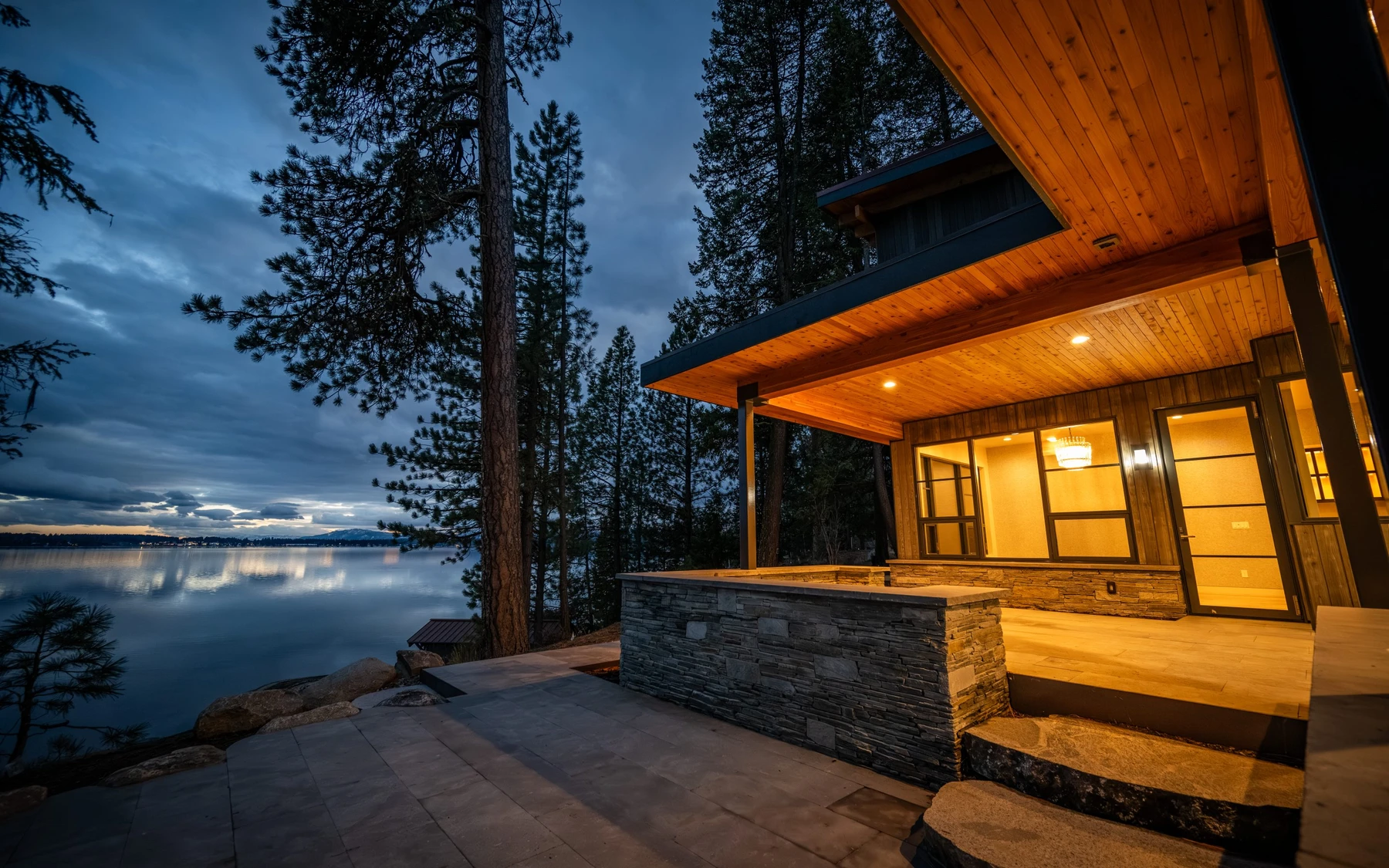 Exterior of the Modern Elegance custom home near McCall, showing wood siding and timber details, stonework, and large windows.