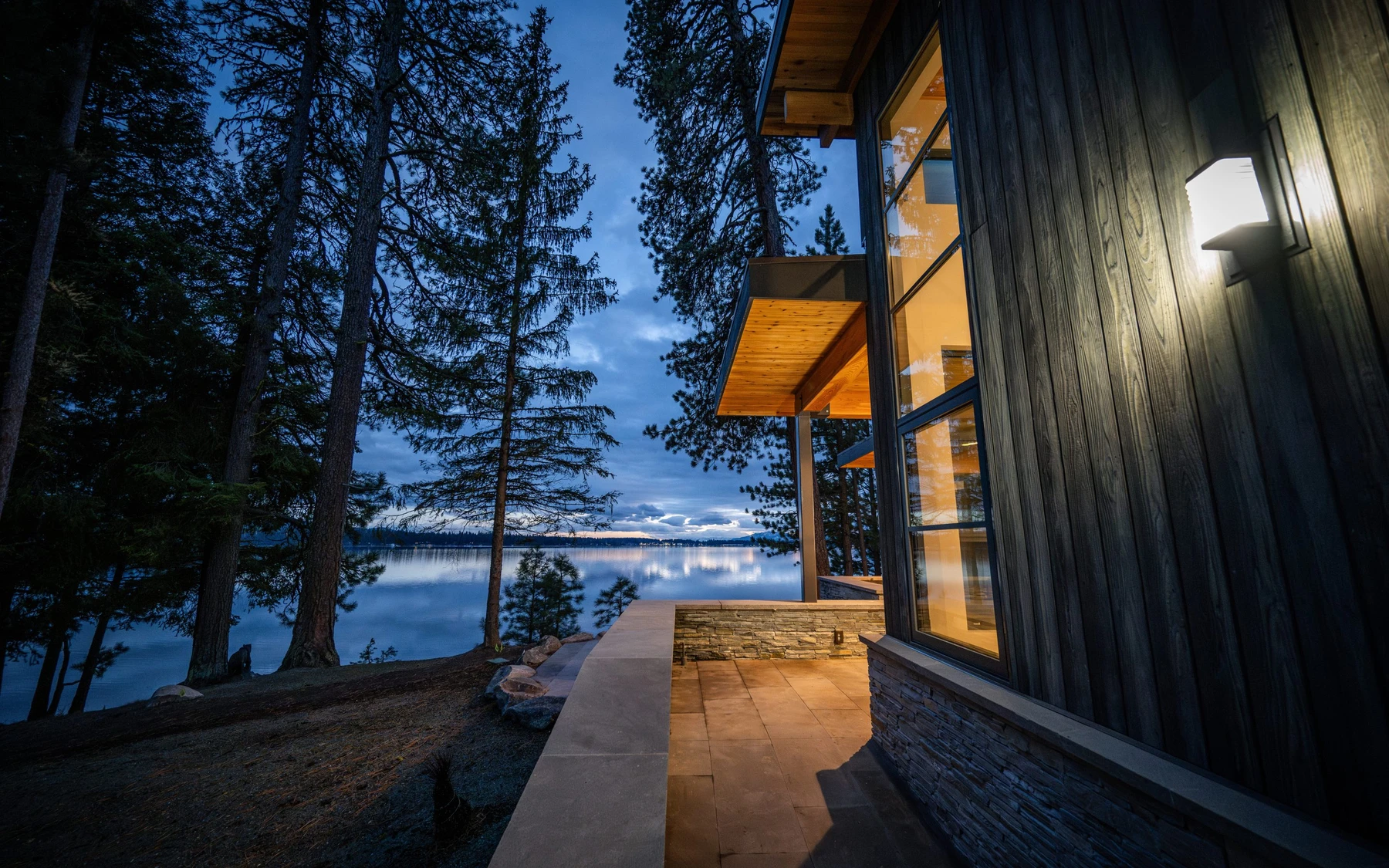 Exterior of the Modern Elegance custom home near McCall, showing wood siding and timber details, large windows, and the lakeside setting.