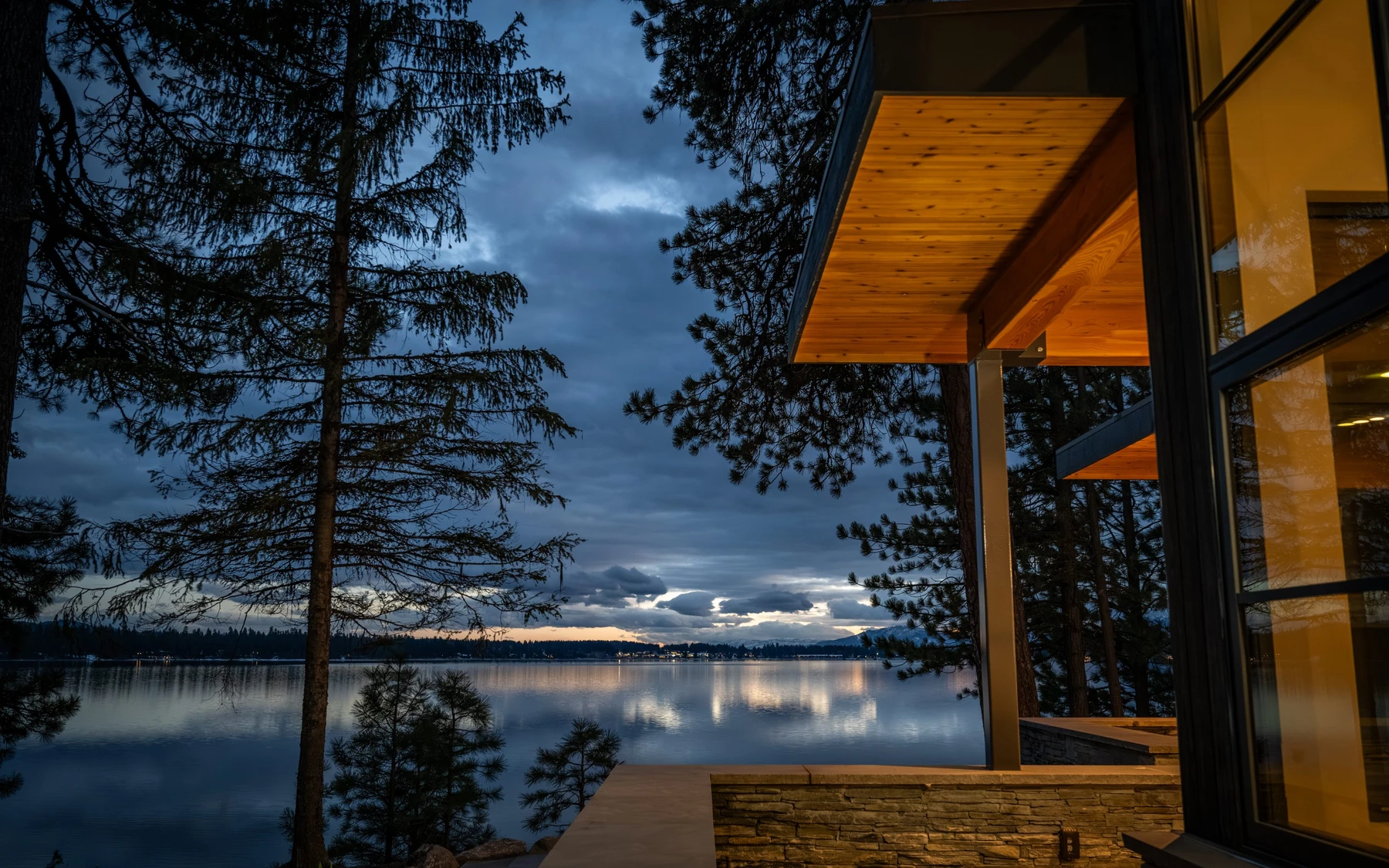 Exterior of the Modern Elegance custom home near McCall, showing wood siding and timber details, large windows, and the lakeside setting.