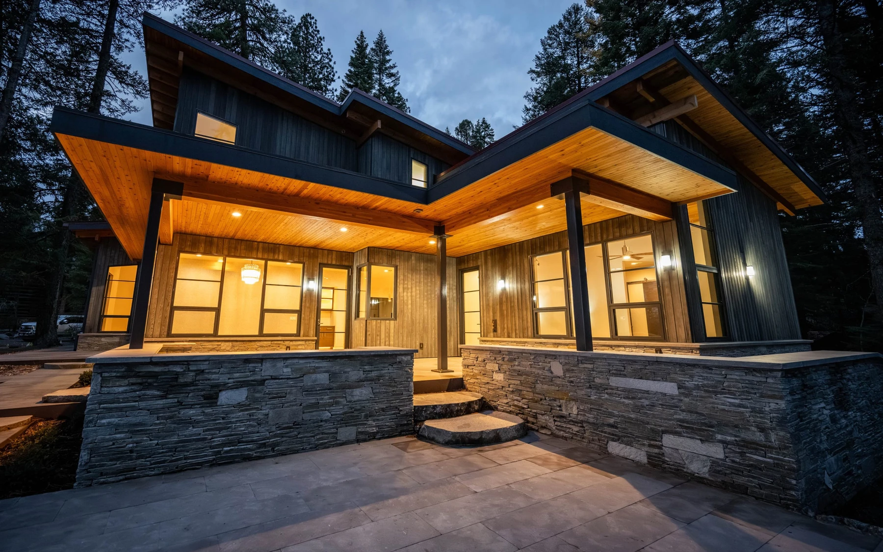 Exterior of the Modern Elegance custom home near McCall, showing wood siding and timber details, stonework, and large windows.