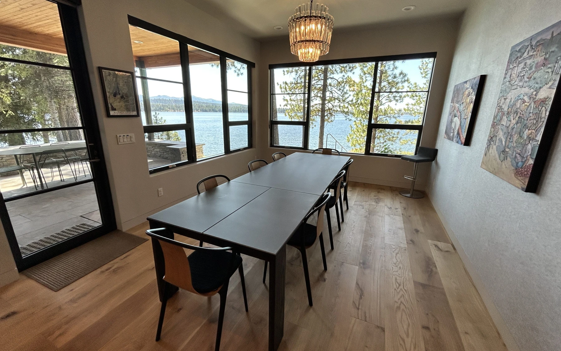 Dining room in the Modern Elegance custom home near McCall, with a dining table, statement lighting, and large windows.