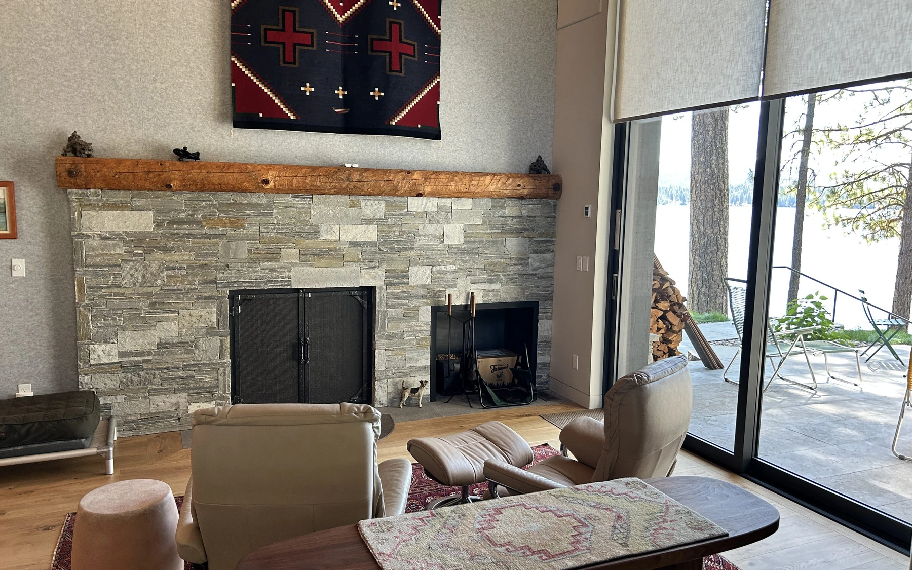Living room in the Modern Elegance custom home near McCall, with a fireplace, a relaxed seating area, and large windows.
