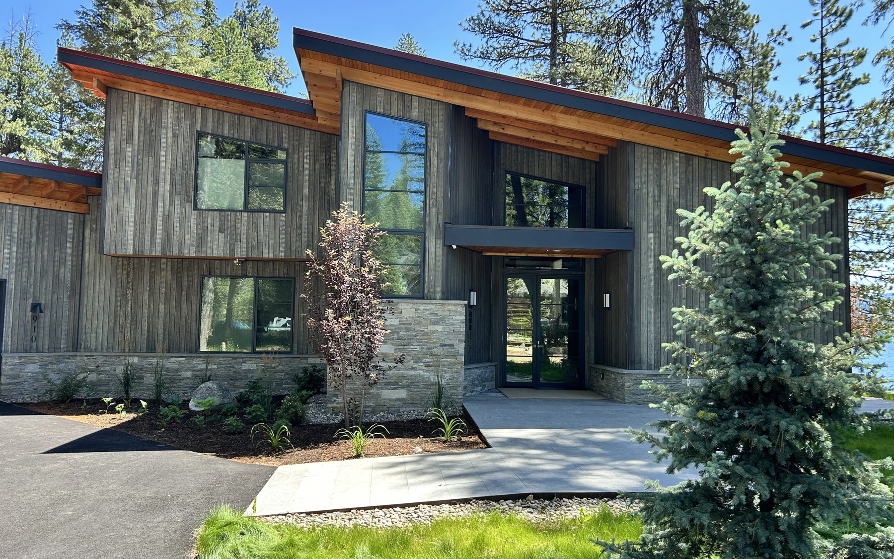 Exterior of the Modern Elegance custom home near McCall, showing wood siding and timber details, large windows, and the surrounding forest.