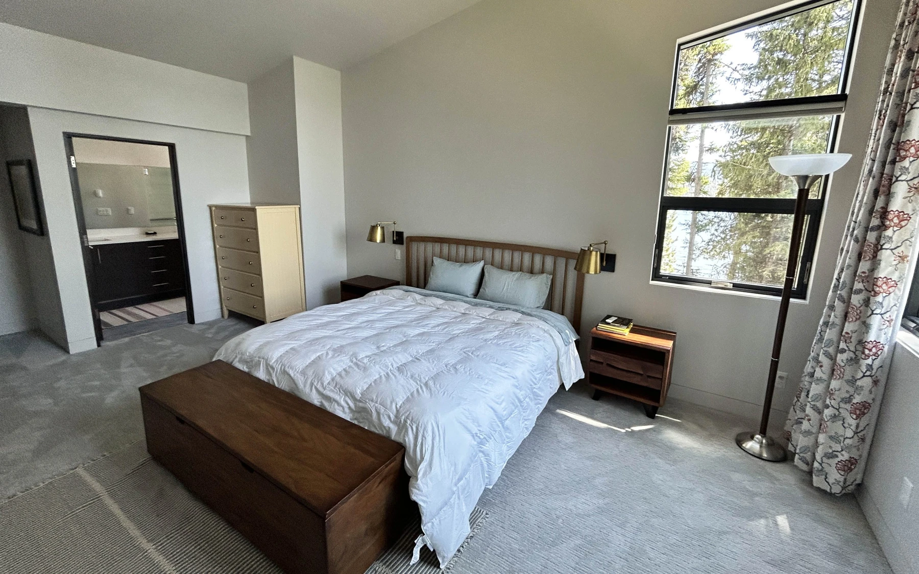 Bedroom in the Modern Elegance custom home near McCall, with a layered bed, large windows, and wood details.