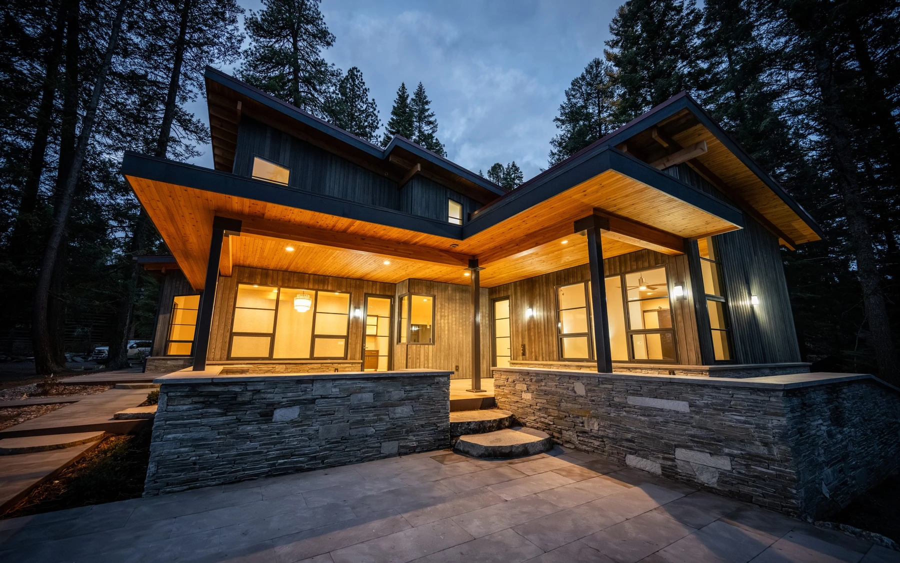 Exterior of the Modern Elegance custom home near McCall, showing wood siding and timber details, stonework, and large windows.
