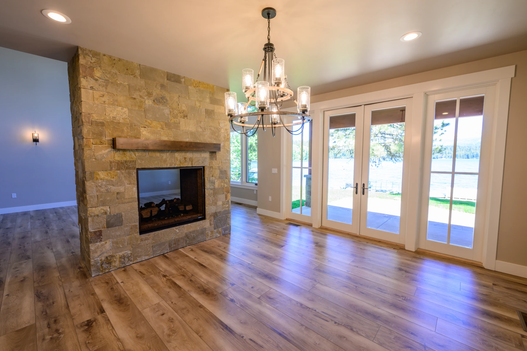 Dining area beside a stone fireplace and paired glass doors opening toward the lake