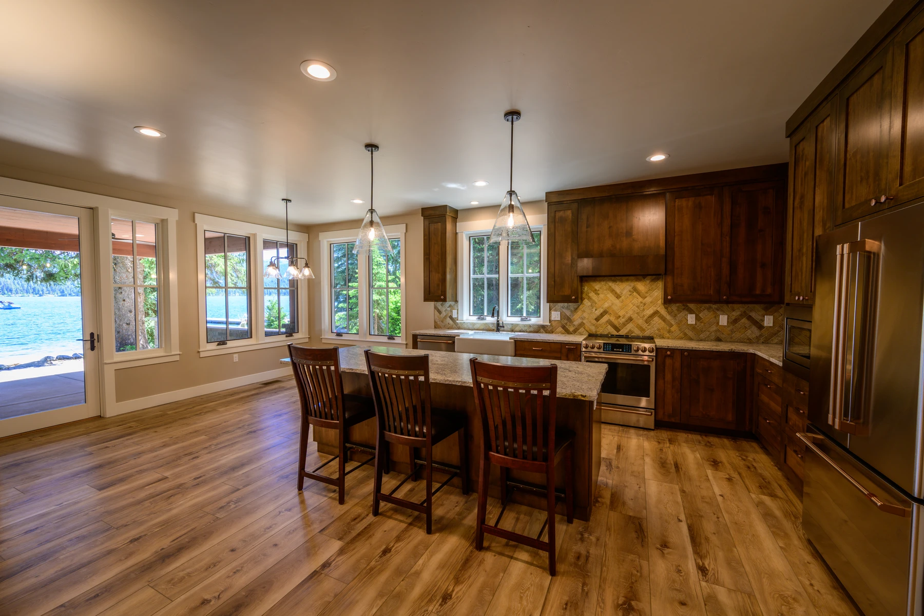 Open kitchen with dark wood cabinetry, stone counters, pendant lights, and a long island