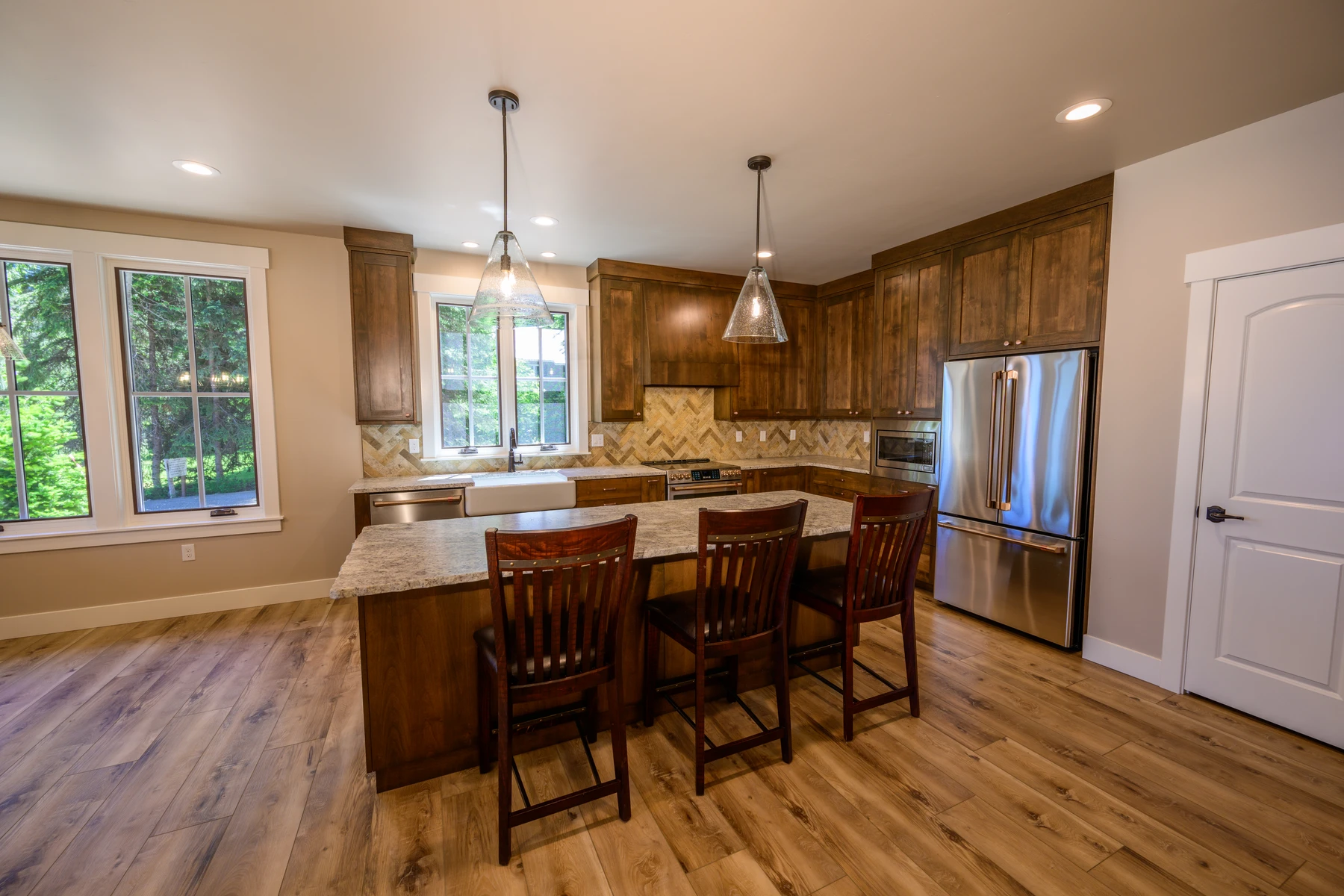 Kitchen and casual dining area with a broad island and windows facing the trees