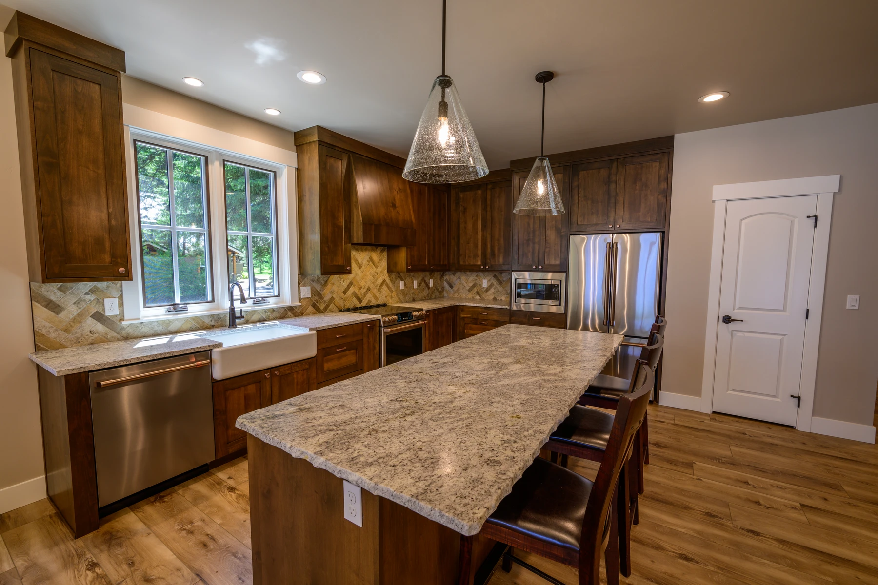 Kitchen sink wall and stone-topped island with windows looking into the pines
