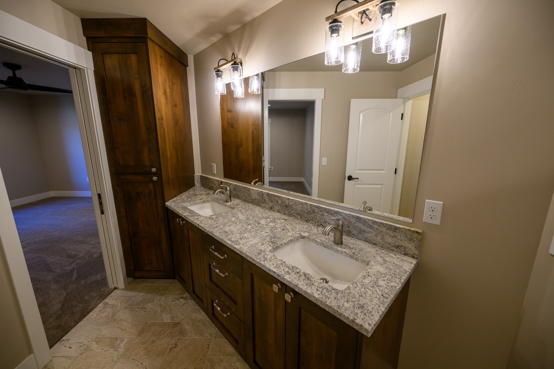 Bathroom vanity with dark wood cabinetry, stone counter, and full-width mirror