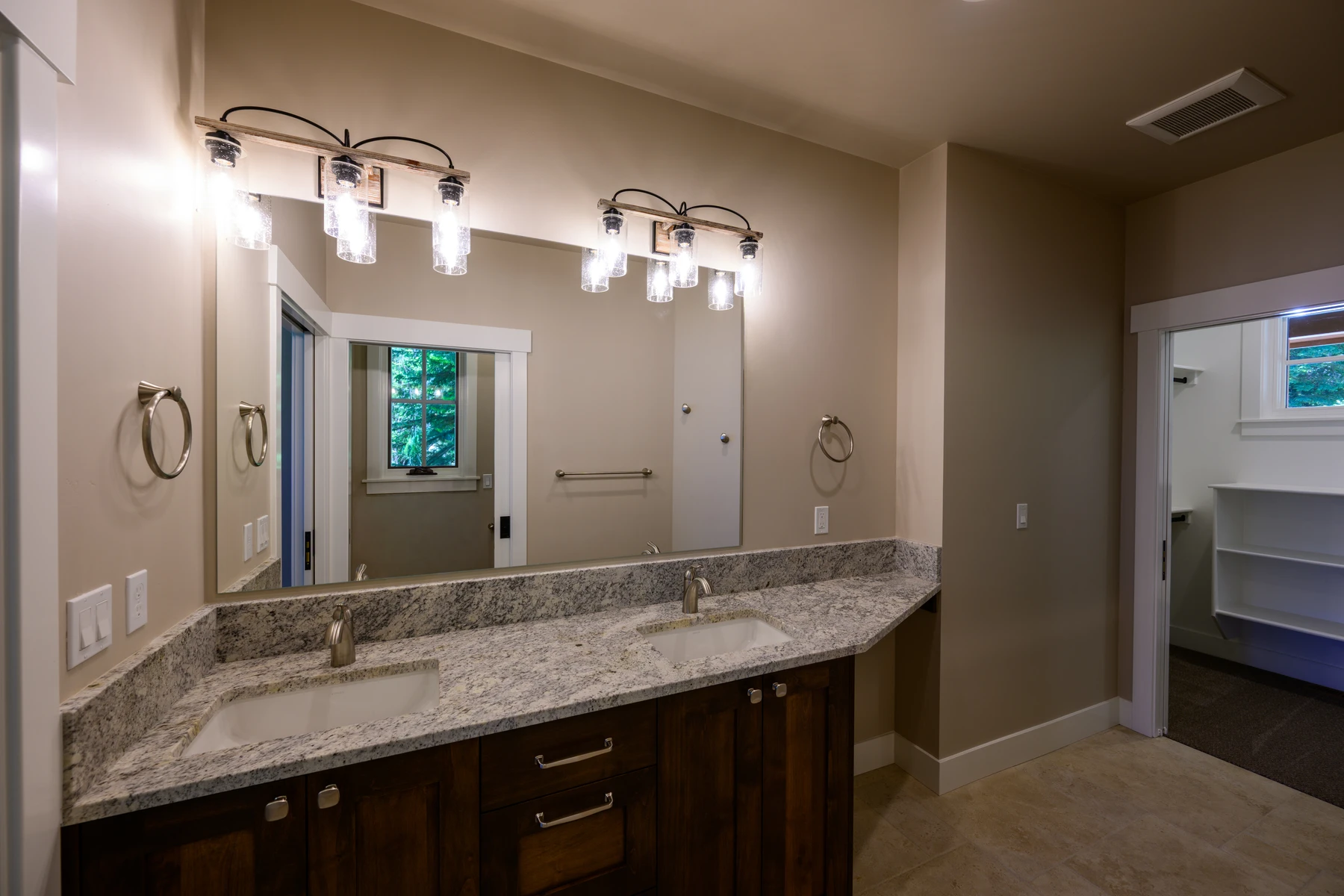 Bathroom with a long double vanity, stone counter, and nearby built-in closet shelving