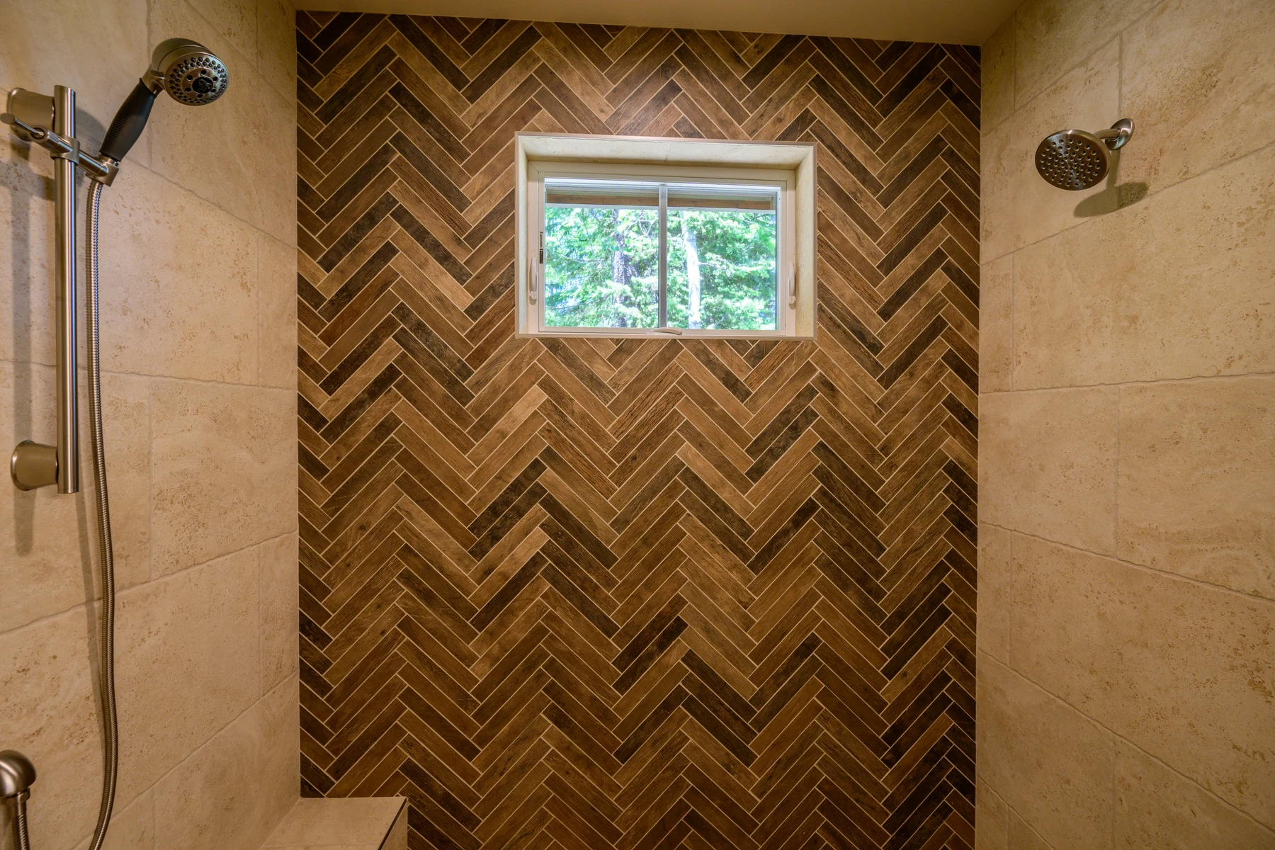 Walk-in shower with dual showerheads and a herringbone wood-look tile feature wall
