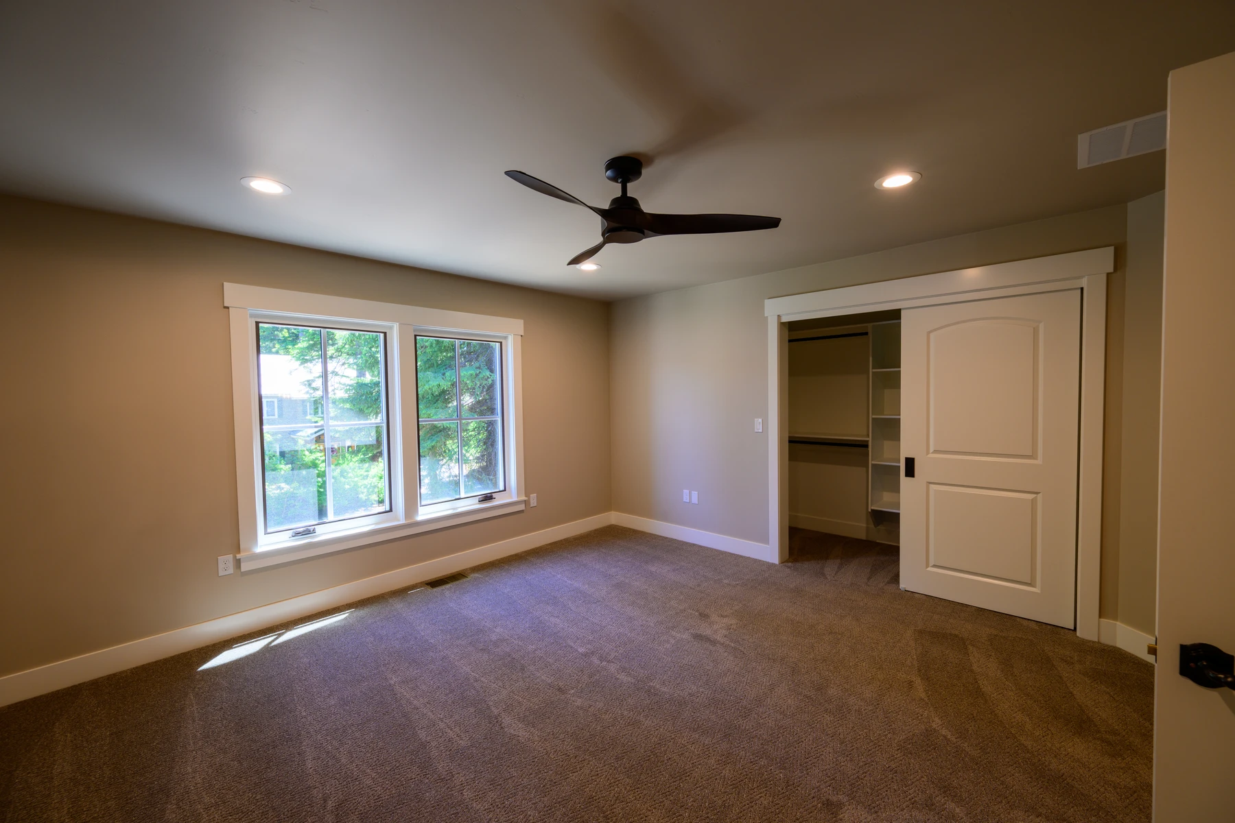 Carpeted bedroom with a wide forest-facing window and walk-in closet