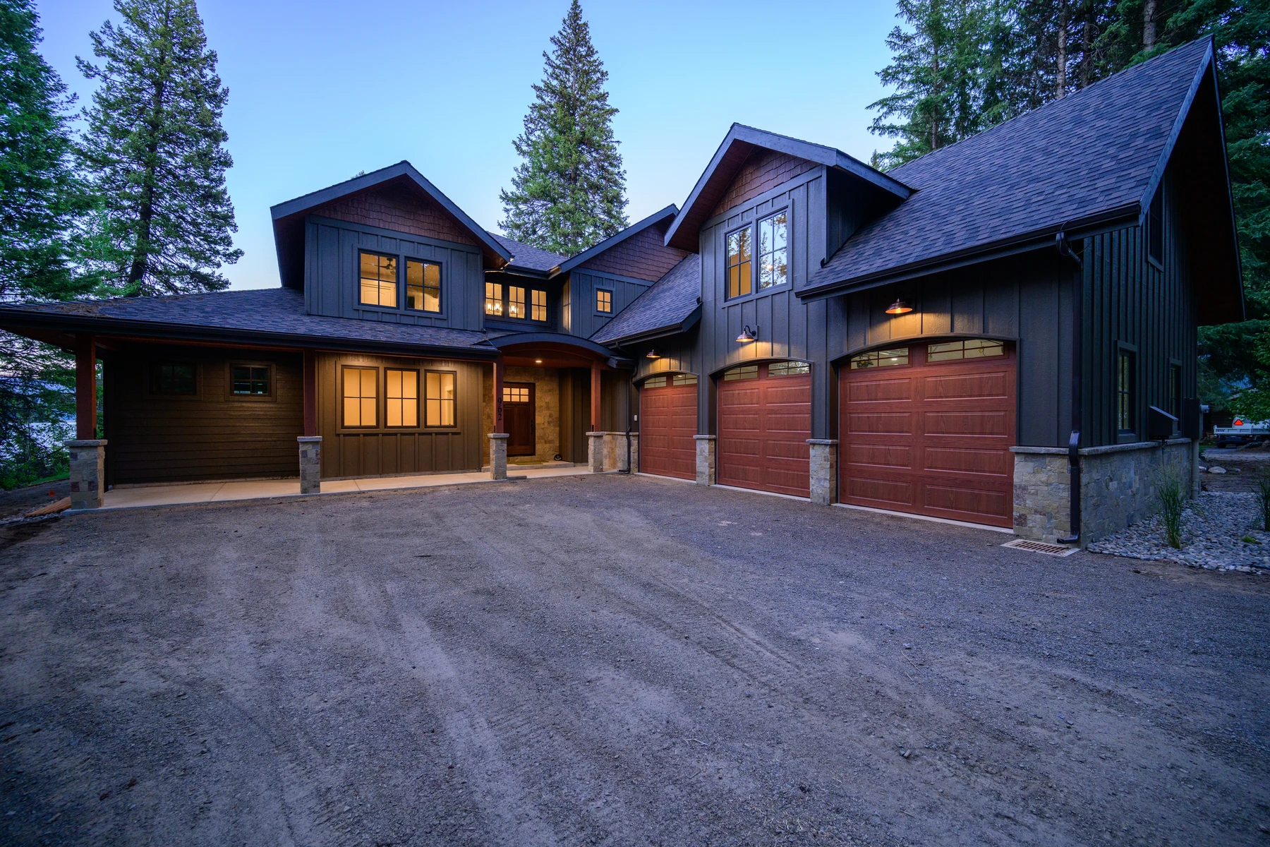 Driveway approach to Pine Shore with three wood garage doors beneath dark gabled roofs
