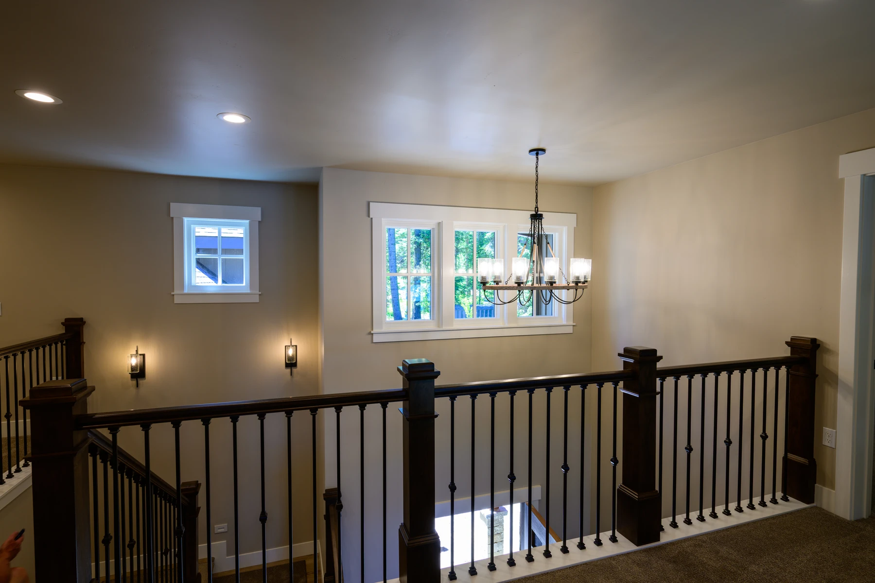 Upper landing with dark wood rails overlooking the tall entry hall
