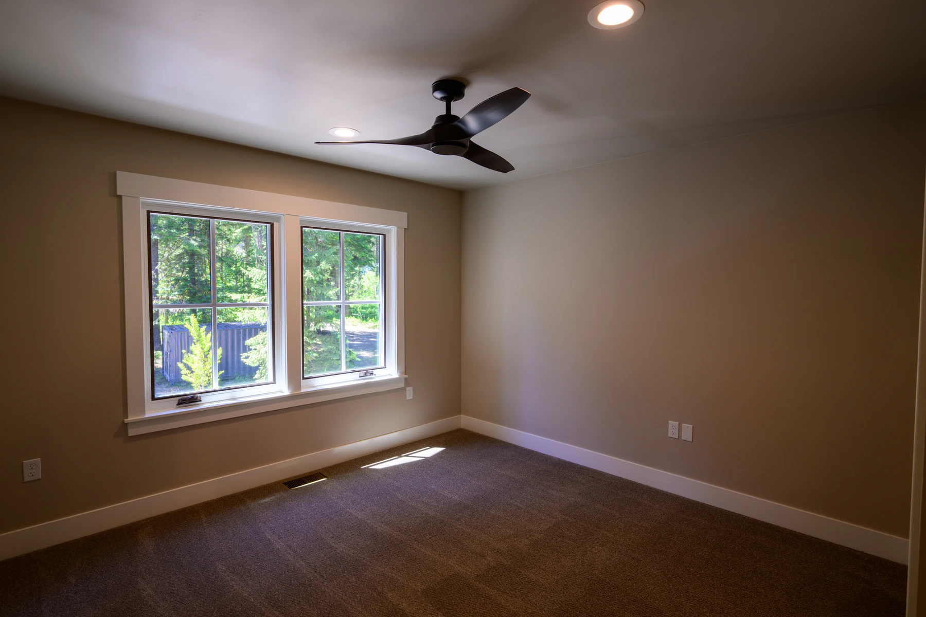 Upper bedroom with a forest-facing window and dark carpet