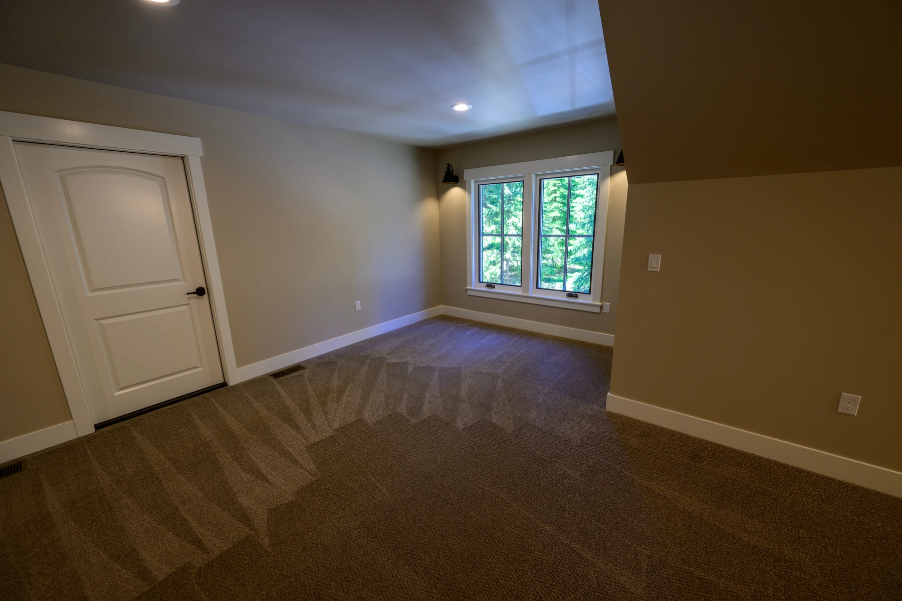 Upper flex room with recessed lighting and a low window toward the forest