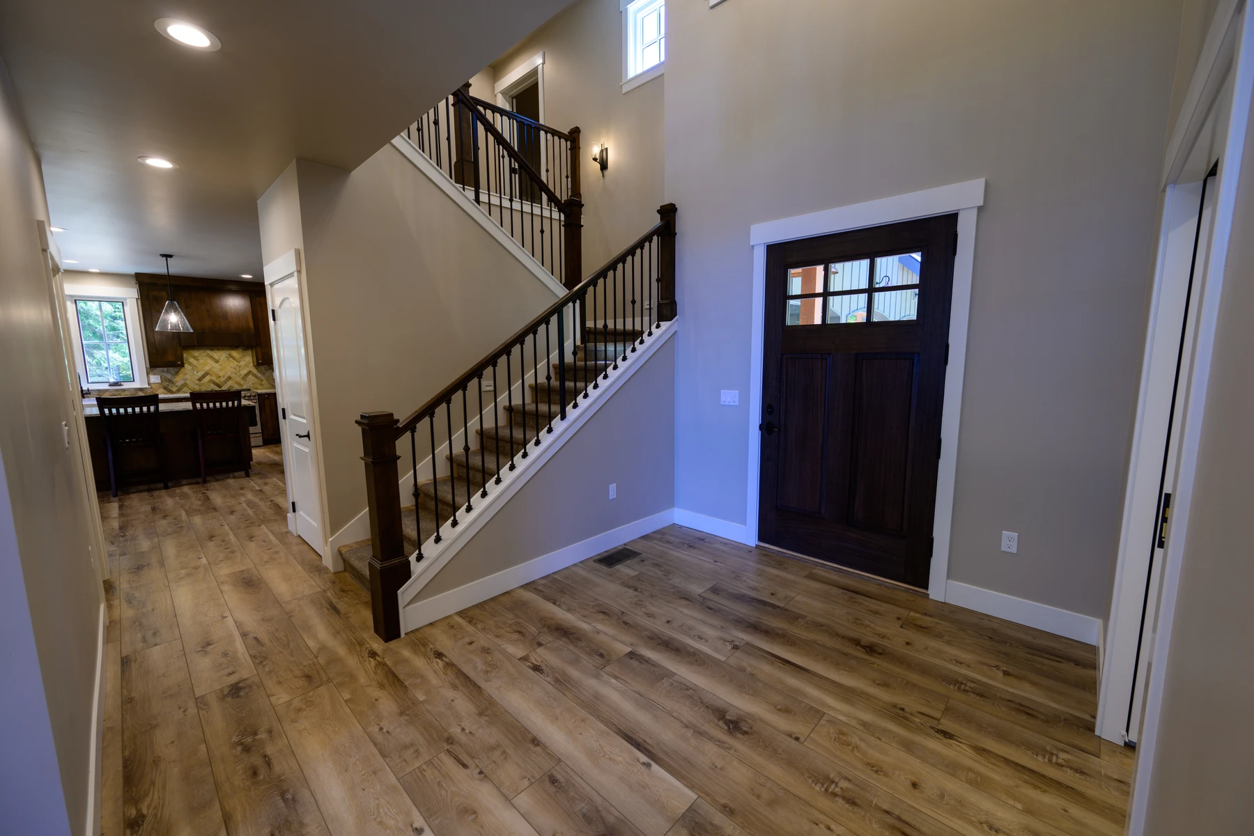 Front entry with wide-plank floors and a dark wood staircase