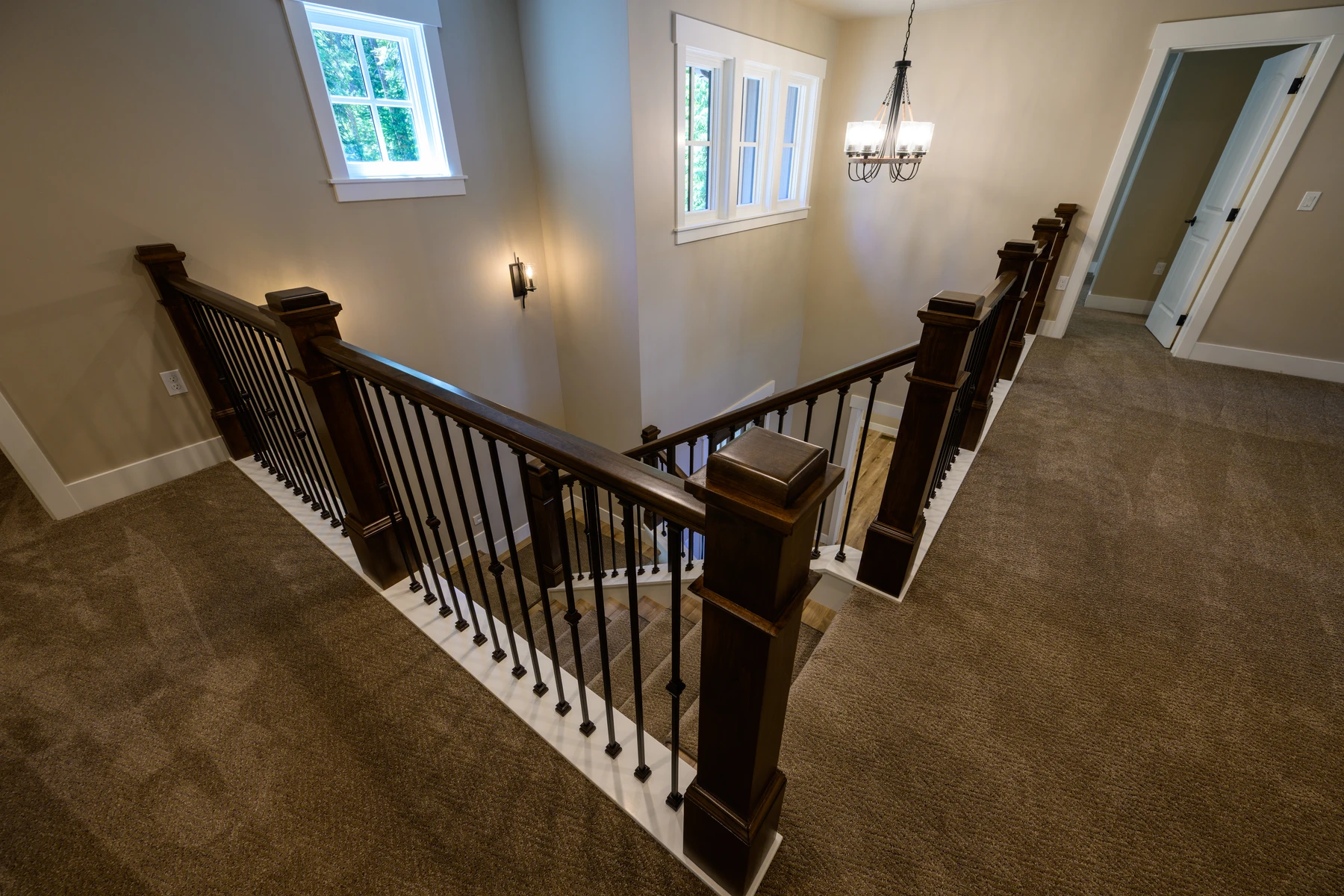 Stair hall with dark wood rails and iron balusters wrapping the upper landing
