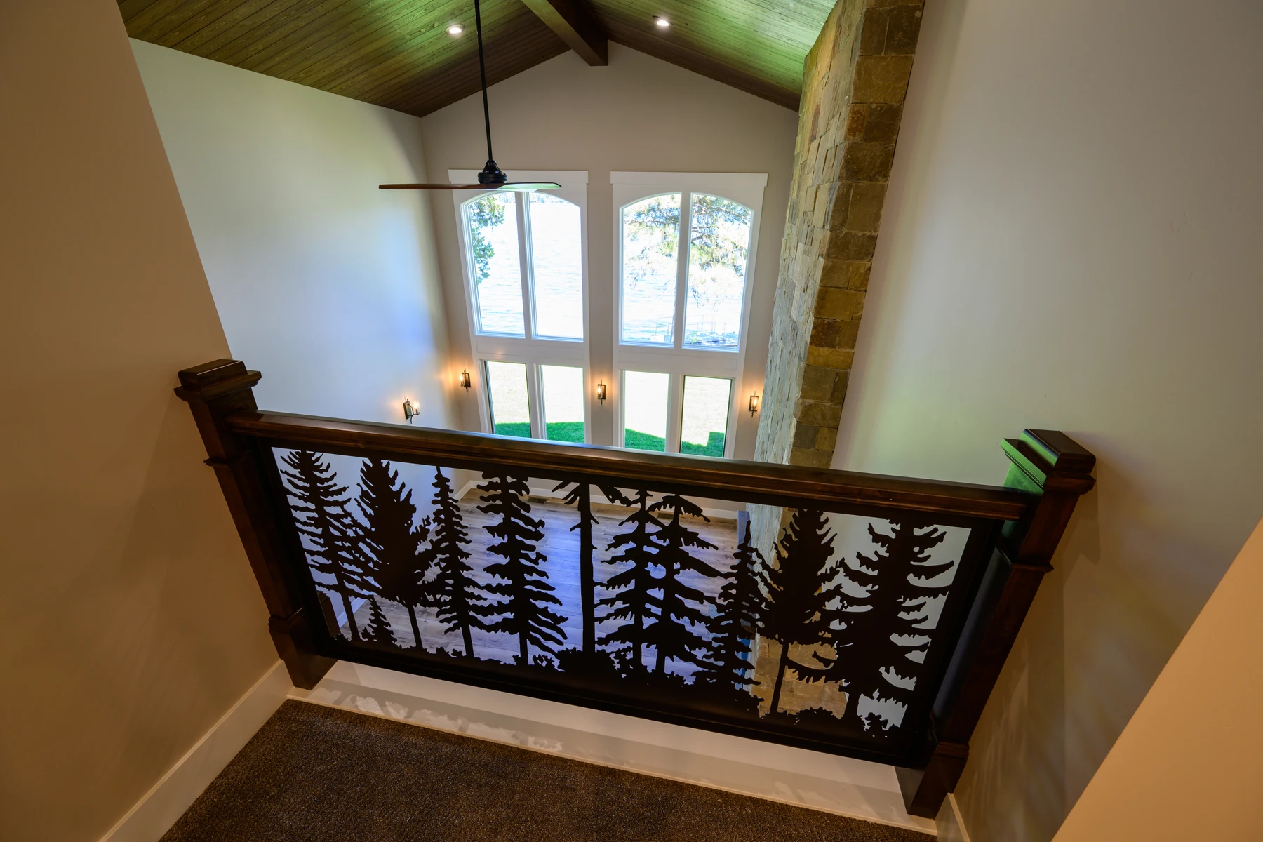 Custom stair railing panel cut with a pine-tree pattern above the great room