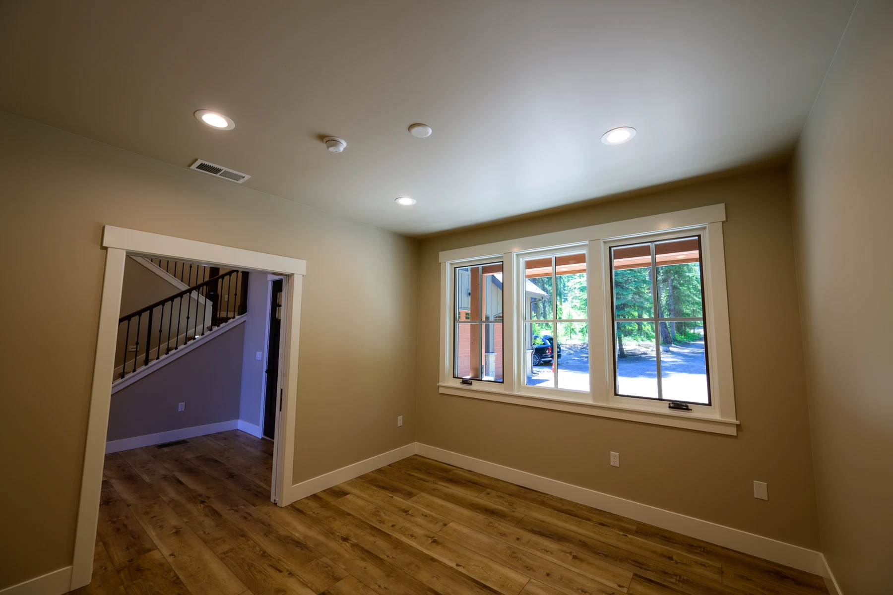 Bright flex room with wide-plank flooring and forest-facing windows