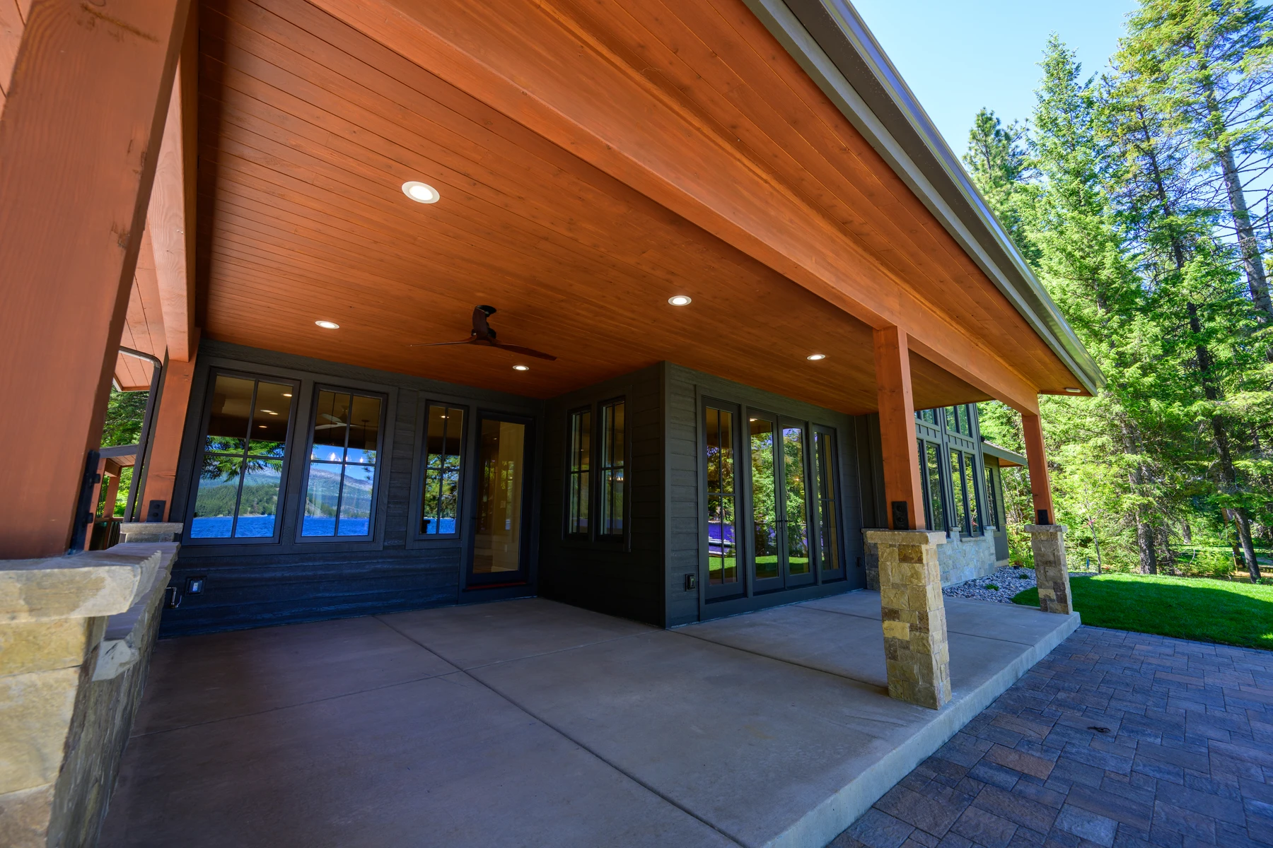 Deep covered patio at Pine Shore with a wood ceiling and views through the trees