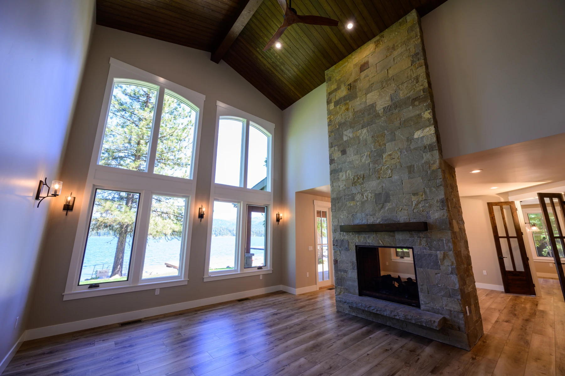 Great room at Pine Shore with tall lake windows and a floor-to-ceiling stone fireplace