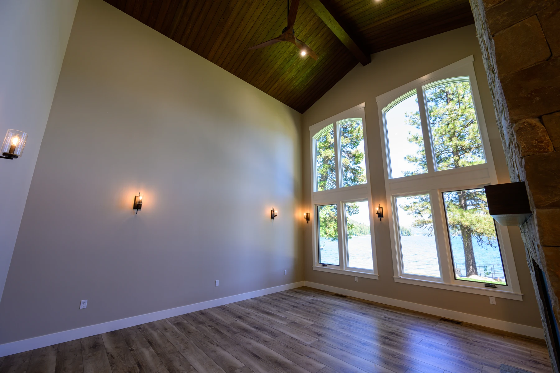 Lake-facing window wall beneath the warm wood ceiling in the great room