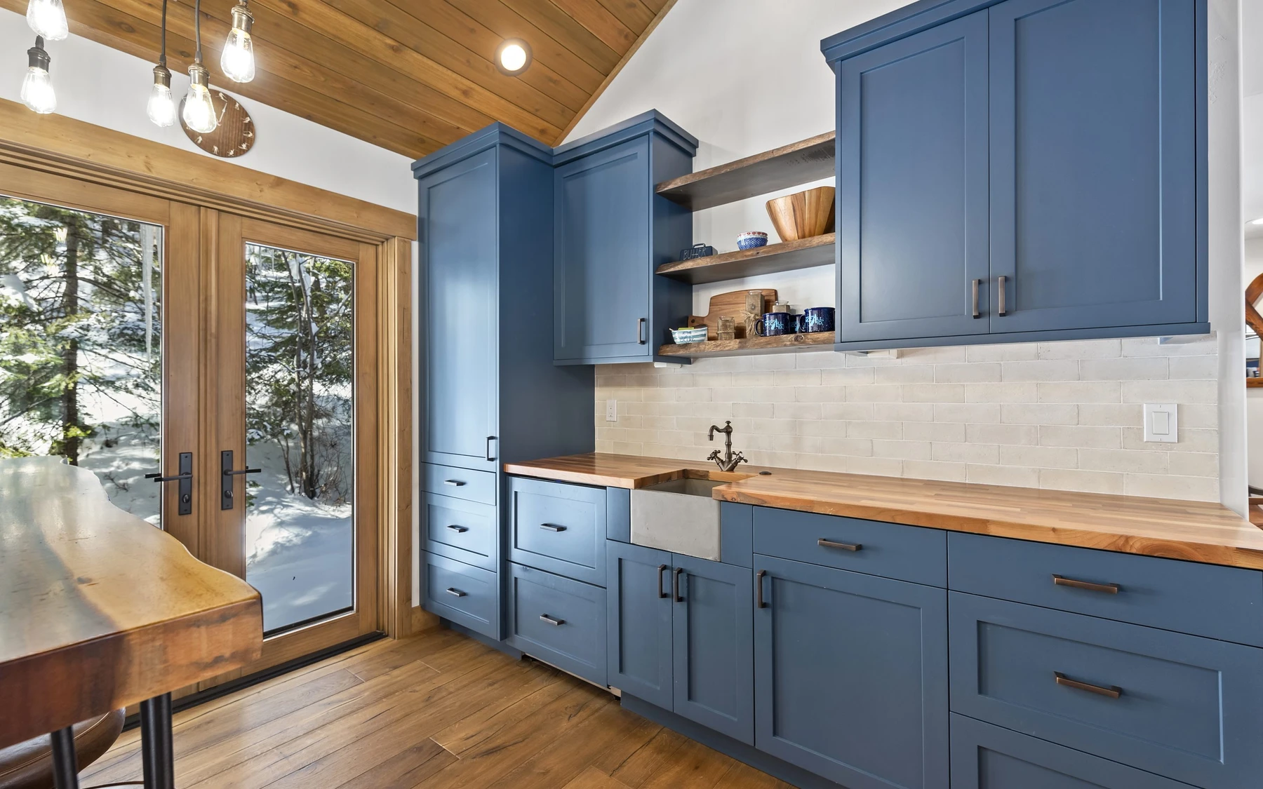 Kitchen in the Plymouth Retreat mountain home near McCall, with wood cabinetry, stone surfaces, and pendant lighting.