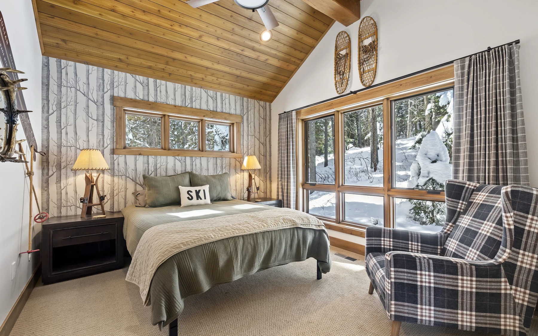 Bedroom in the Plymouth Retreat mountain home near McCall, with a layered bed, large windows, and wood details.
